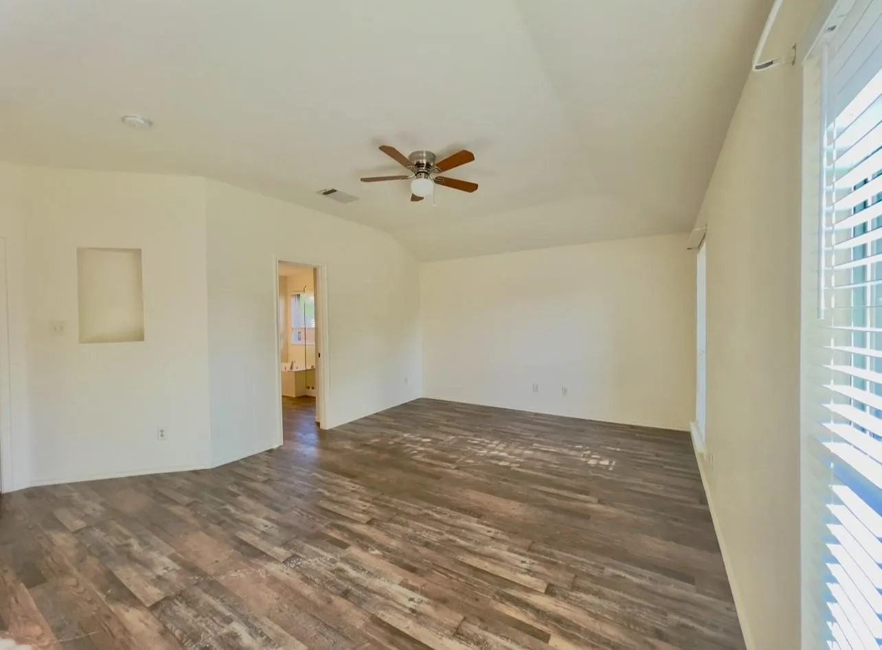 Spacious interior featuring wood-finish flooring, a ceiling fan, recessed lighting, and a built-in wall niche