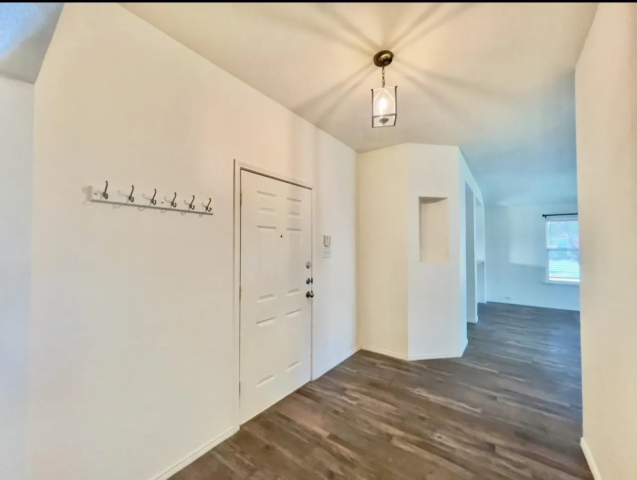 Entryway featuring wood-finish flooring, a paneled door, and a built-in wall niche
