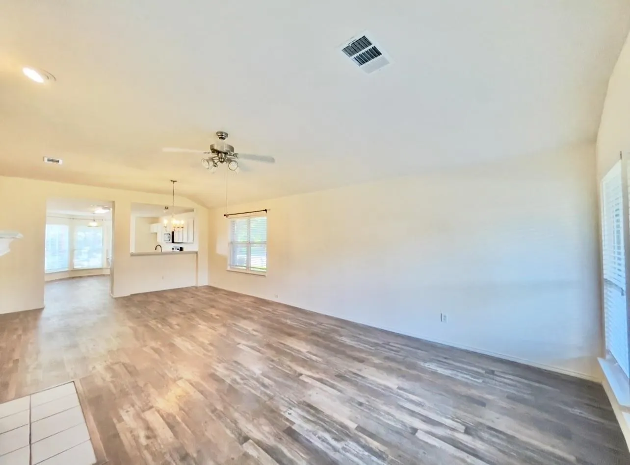Wood-finish flooring throughout, ceiling fan with light fixture, recessed lighting, and white window shutters