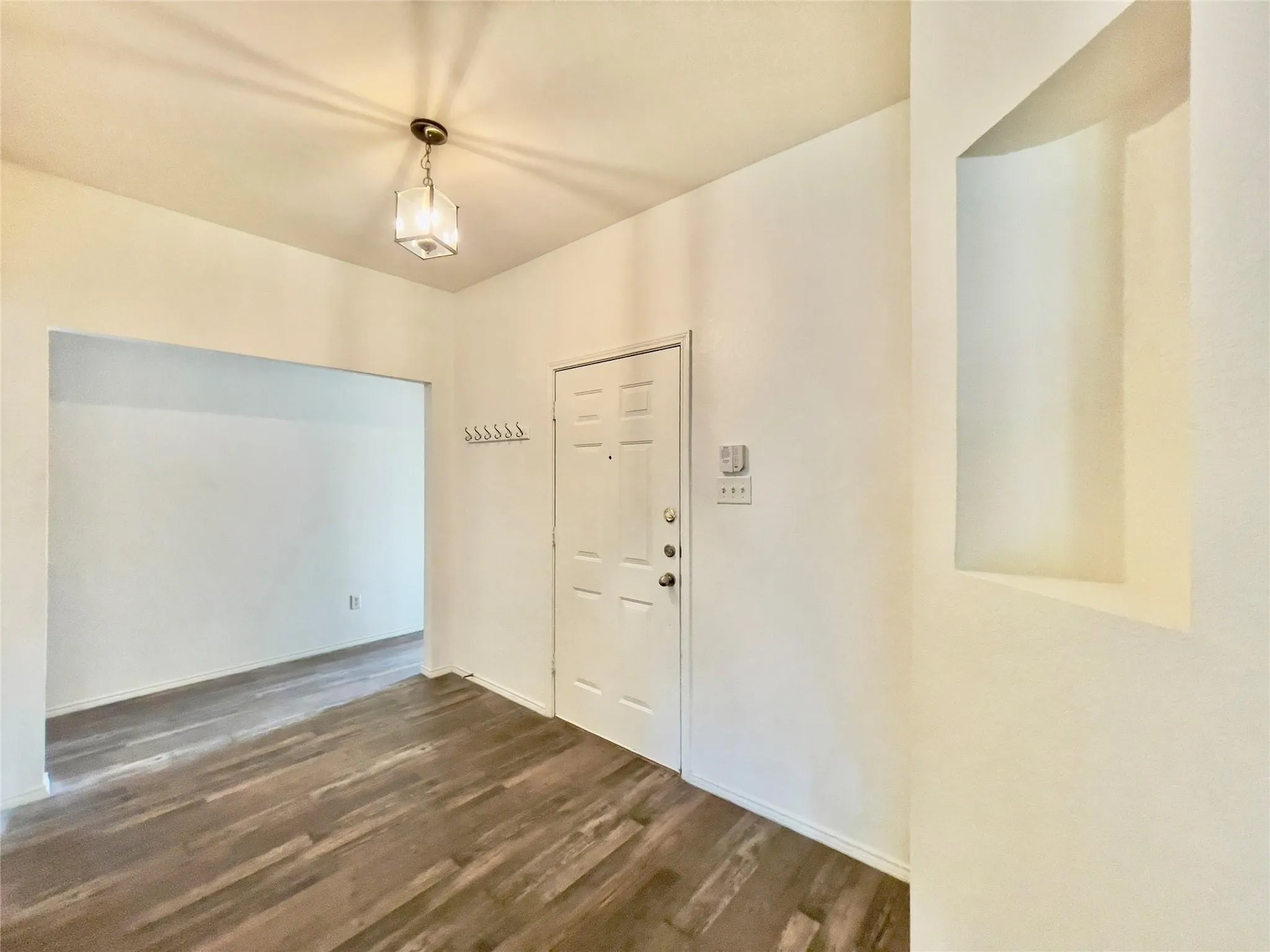 Wood-finish flooring throughout, with a recessed wall niche, and an overhead decorative light fixture