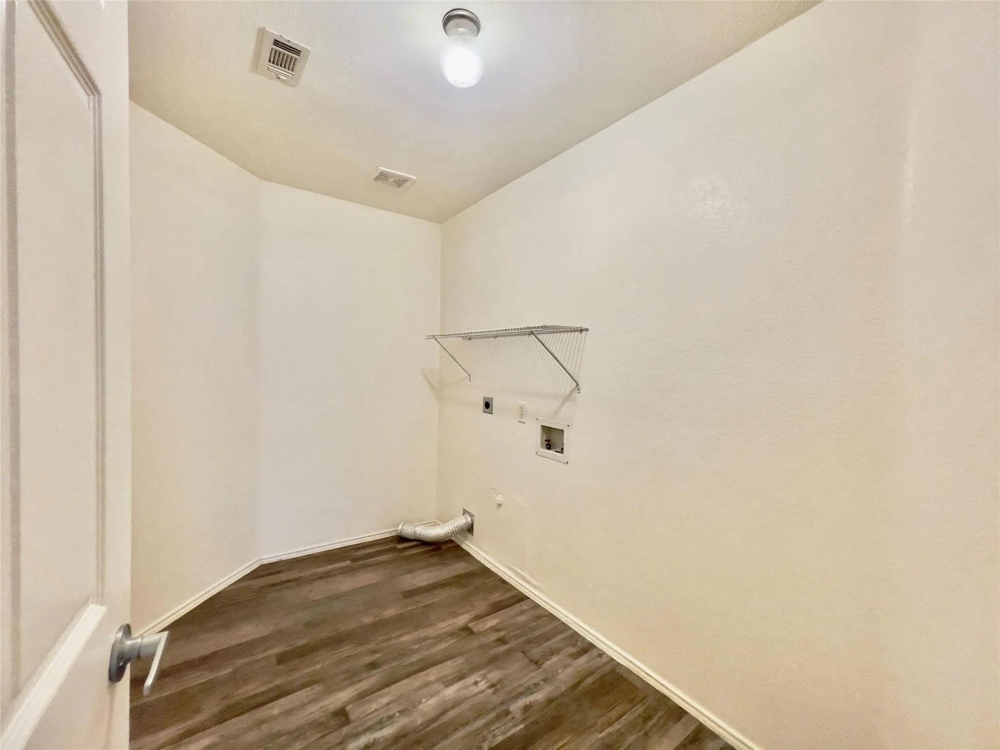Laundry room featuring wood-finish flooring, a wire shelf, and an overhead light fixture