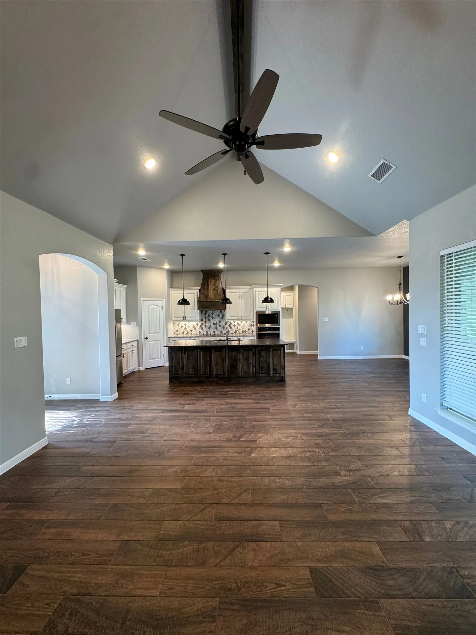 Vaulted ceiling with exposed beam and ceiling fan, wood-finish flooring, recessed lighting, and kitchen island with pendant lighting