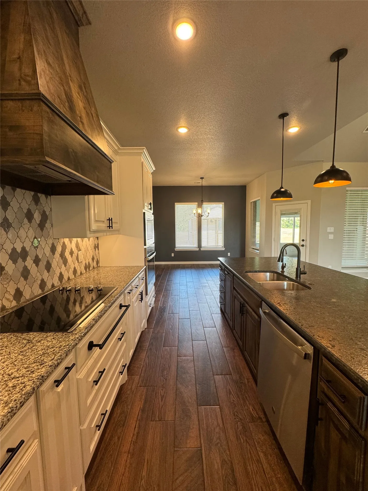 Gourmet kitchen with wood-finish flooring, light-toned cabinetry, granite countertops, and a tile backsplash