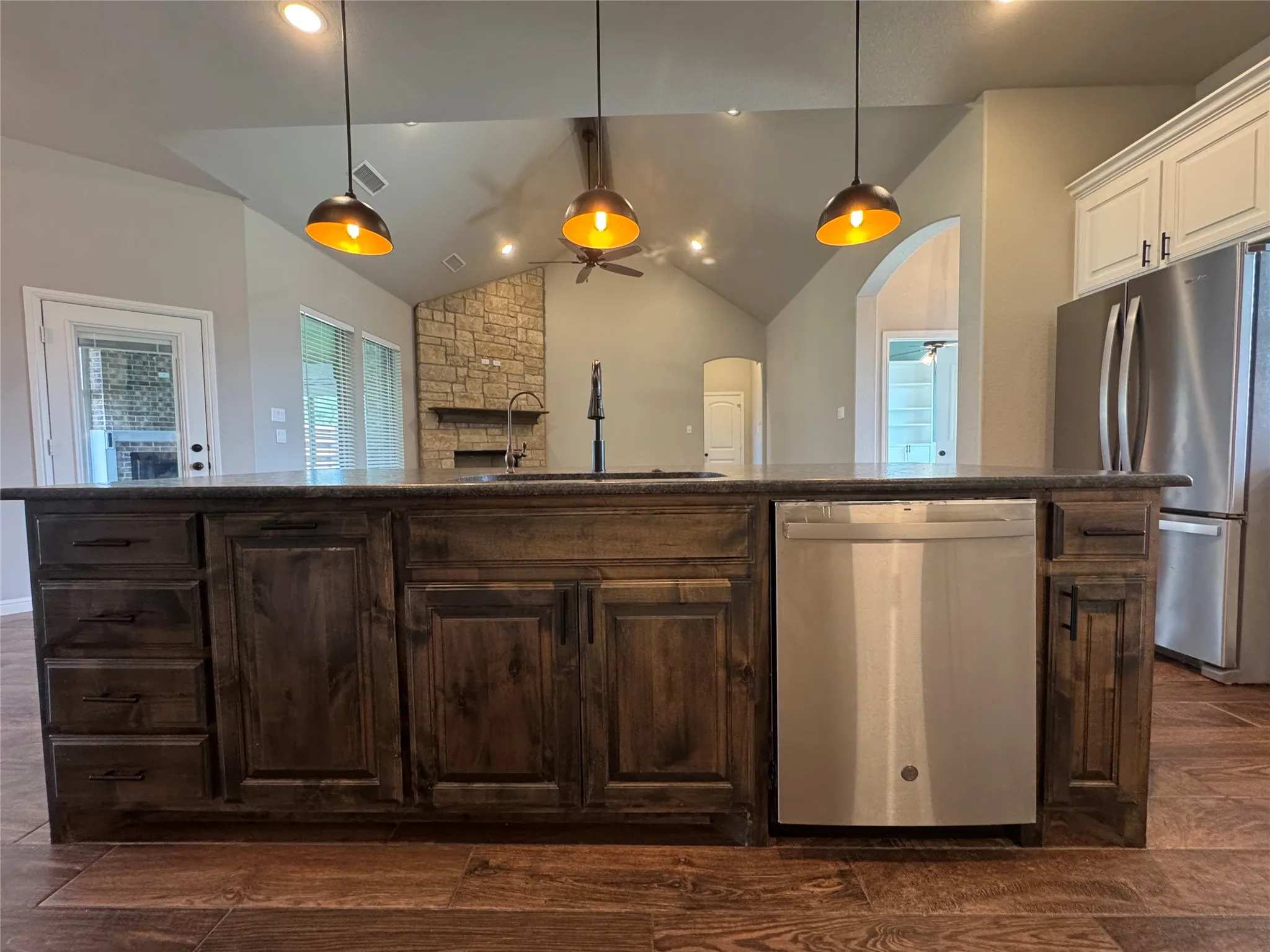 Chef's kitchen featuring a substantial dark wood cabinetry island with integrated stainless steel dishwasher, paired with matching perimeter cabinetry and quartz countertops