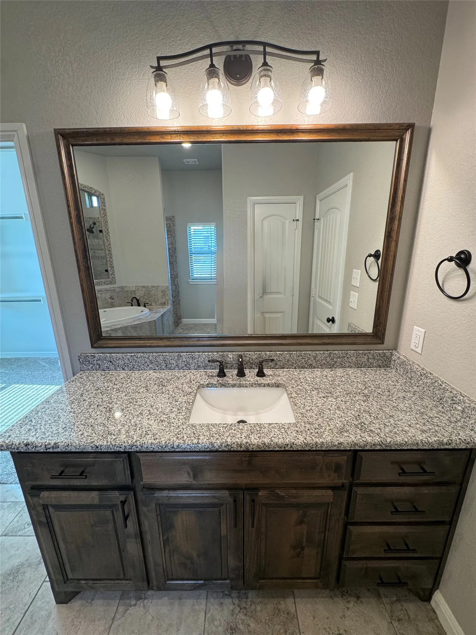 Single vanity with a granite countertop, undermount sink, and dark wood-finish cabinetry