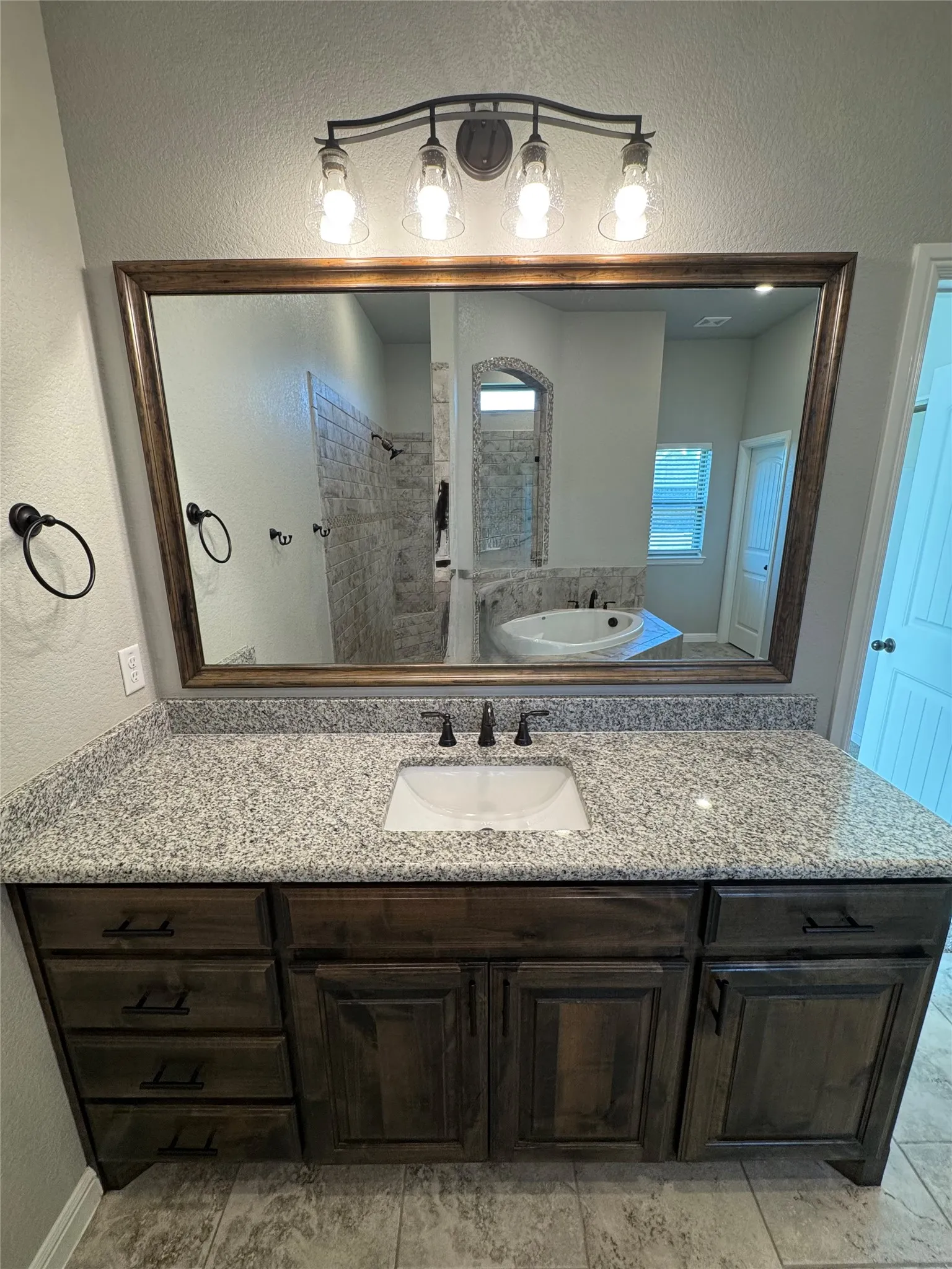 Vanity with a granite-style countertop, undermount sink, and dark wood-finish cabinetry