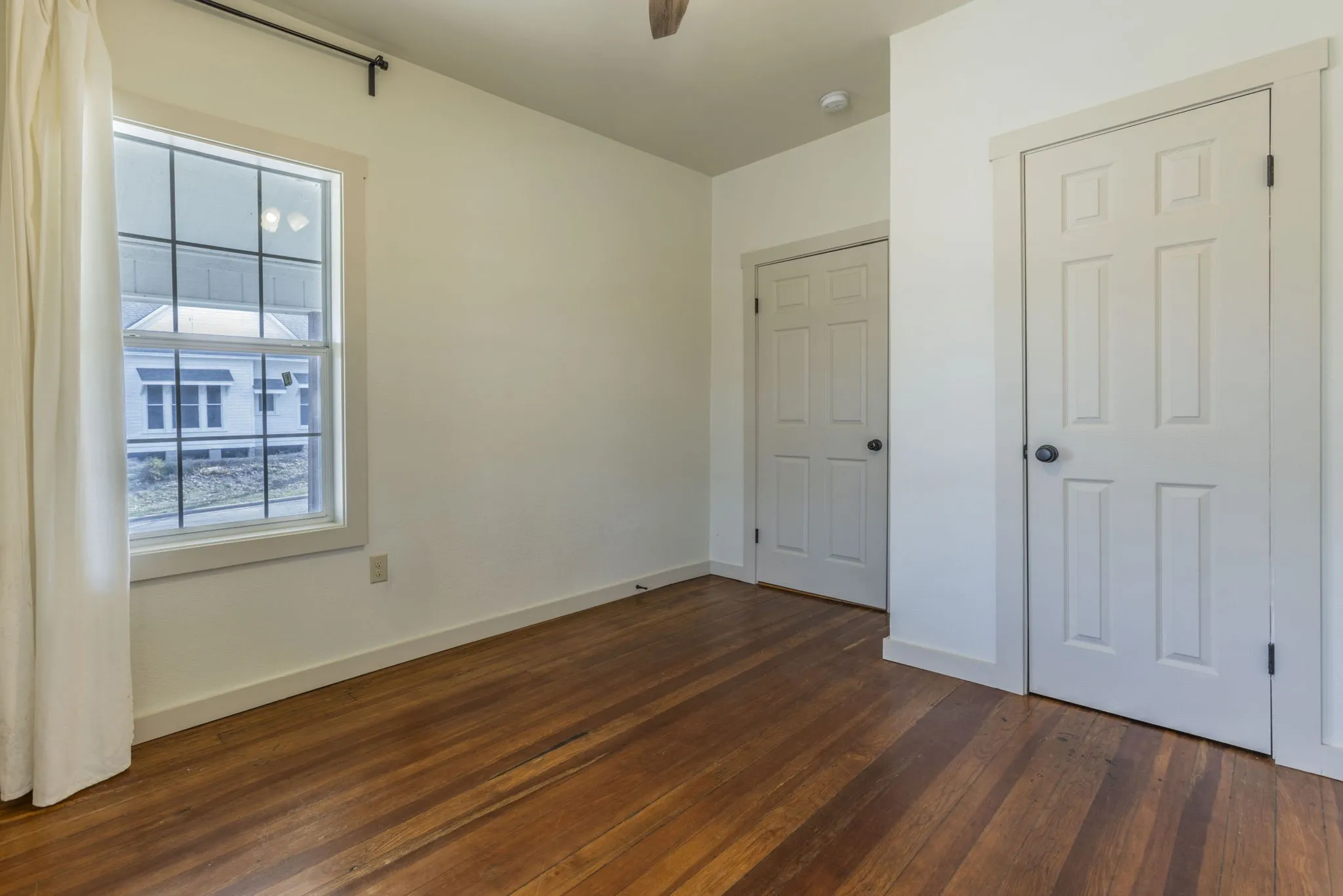 Room featuring wood-finish flooring, white walls, and a multi-pane window