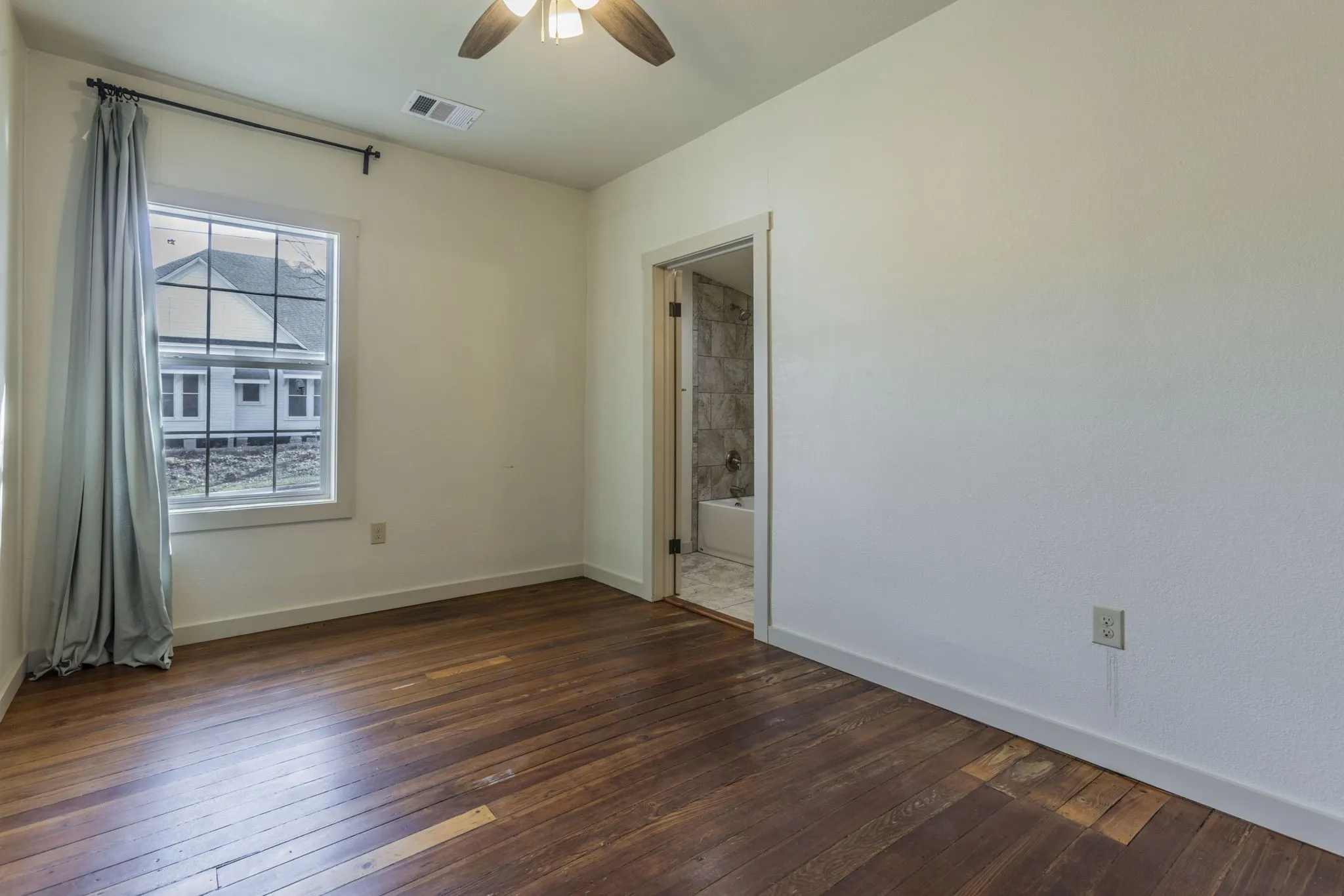 Room featuring warm wood-finish flooring, a contemporary ceiling fan with integrated lighting, and a window with white trim