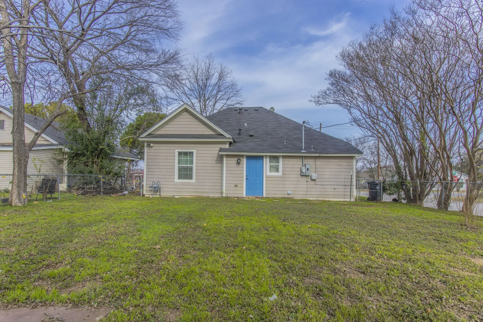 Rear exterior featuring light-toned siding and a contrasting blue entry door
