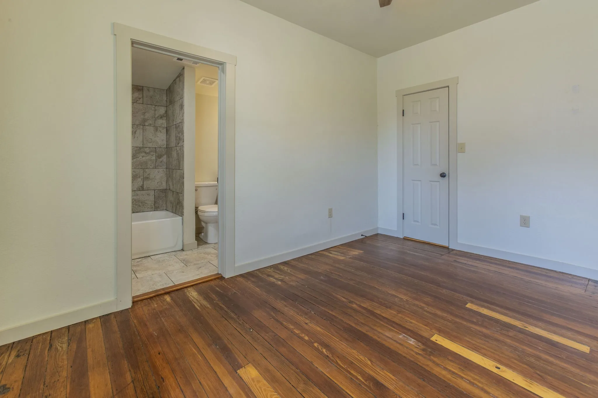 Hardwood flooring throughout the room, with white baseboards and trim