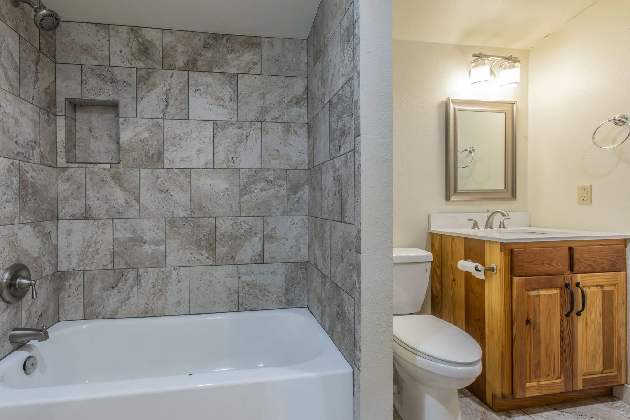 Bathroom featuring a tub/shower combination with large format tile surround and recessed niche