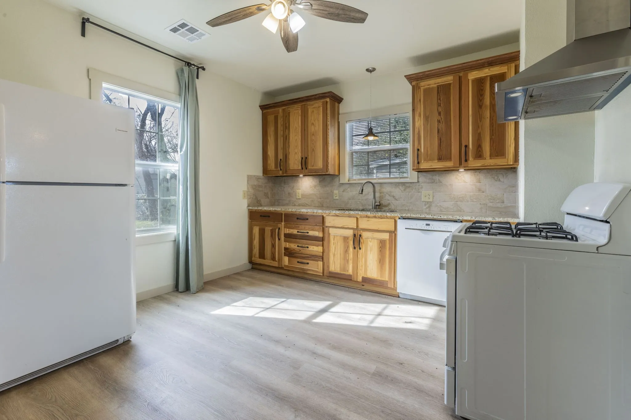 Kitchen featuring wood-finish cabinetry, light-toned countertops, and a tiled backsplash