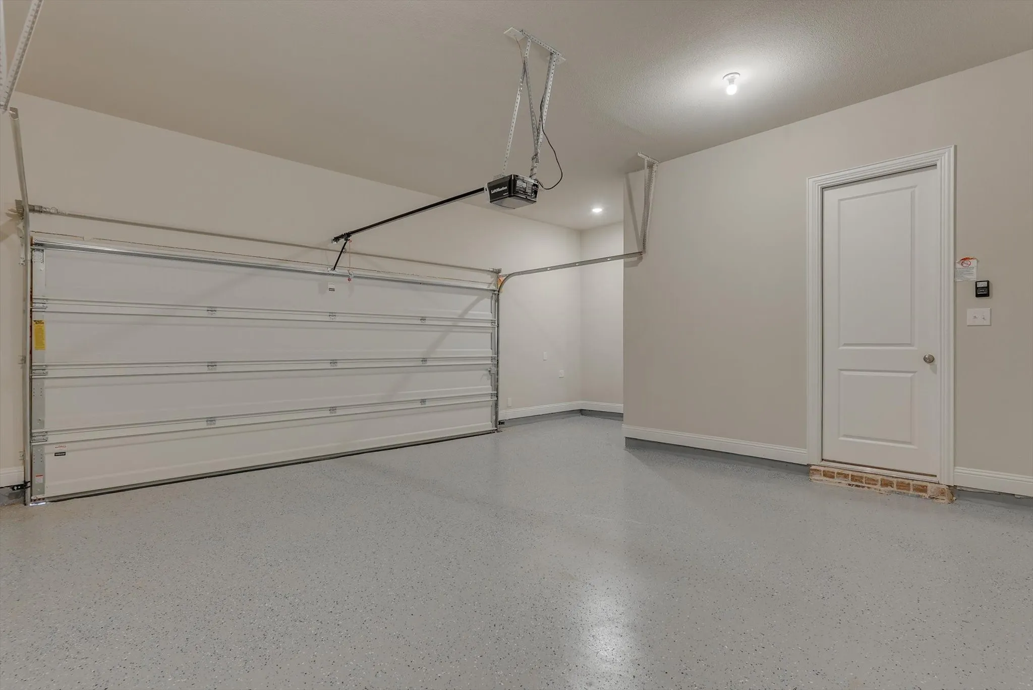 Spacious garage featuring a finished floor coating, automatic garage door opener, recessed lighting, and a white paneled door