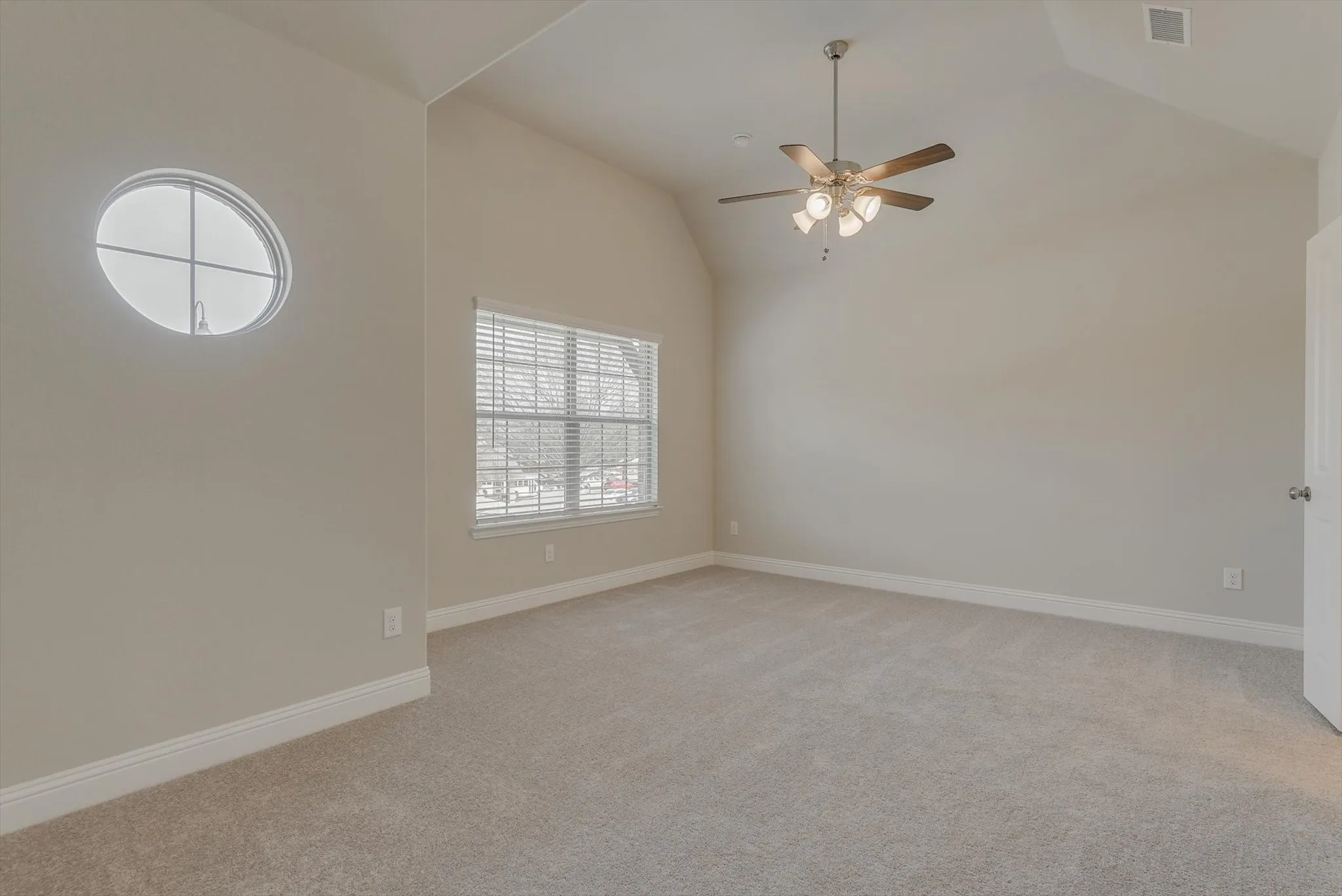 Vaulted ceilings, a contemporary ceiling fan, and light gray carpet