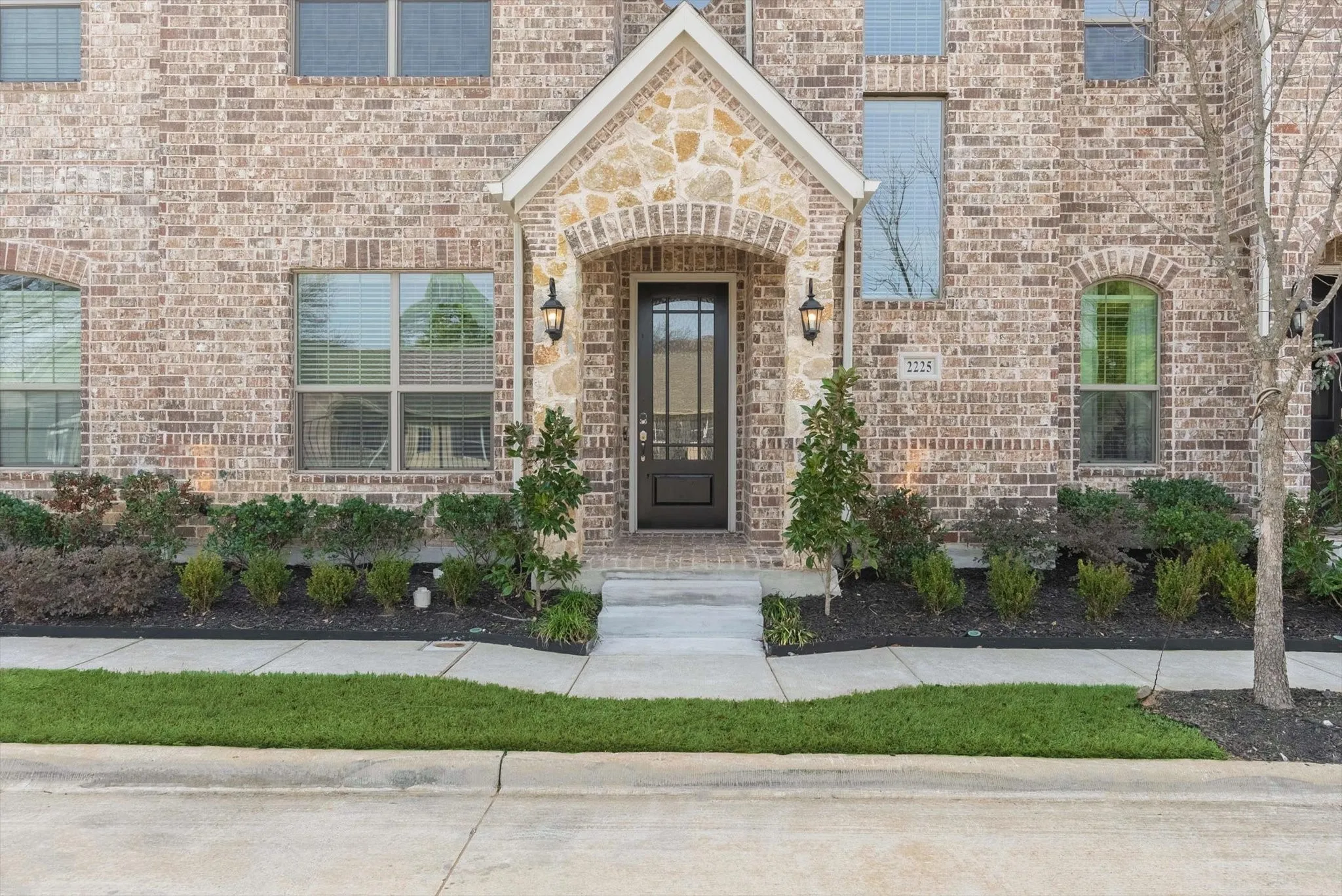 Brick exterior with stone accents, featuring a prominent front entrance with a dark-paneled door
