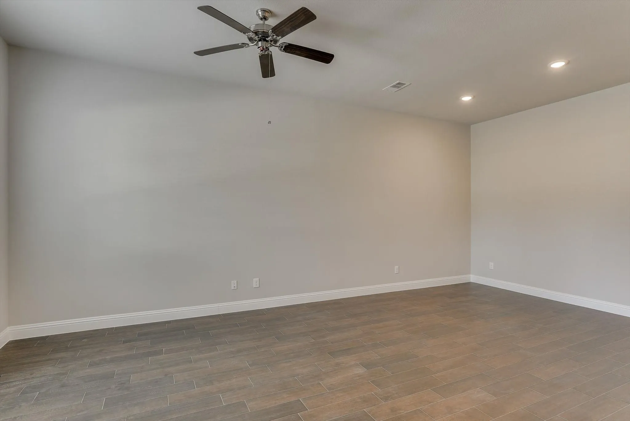 Spacious interior with wood-finish flooring, neutral wall tones, recessed lighting, and a ceiling fan