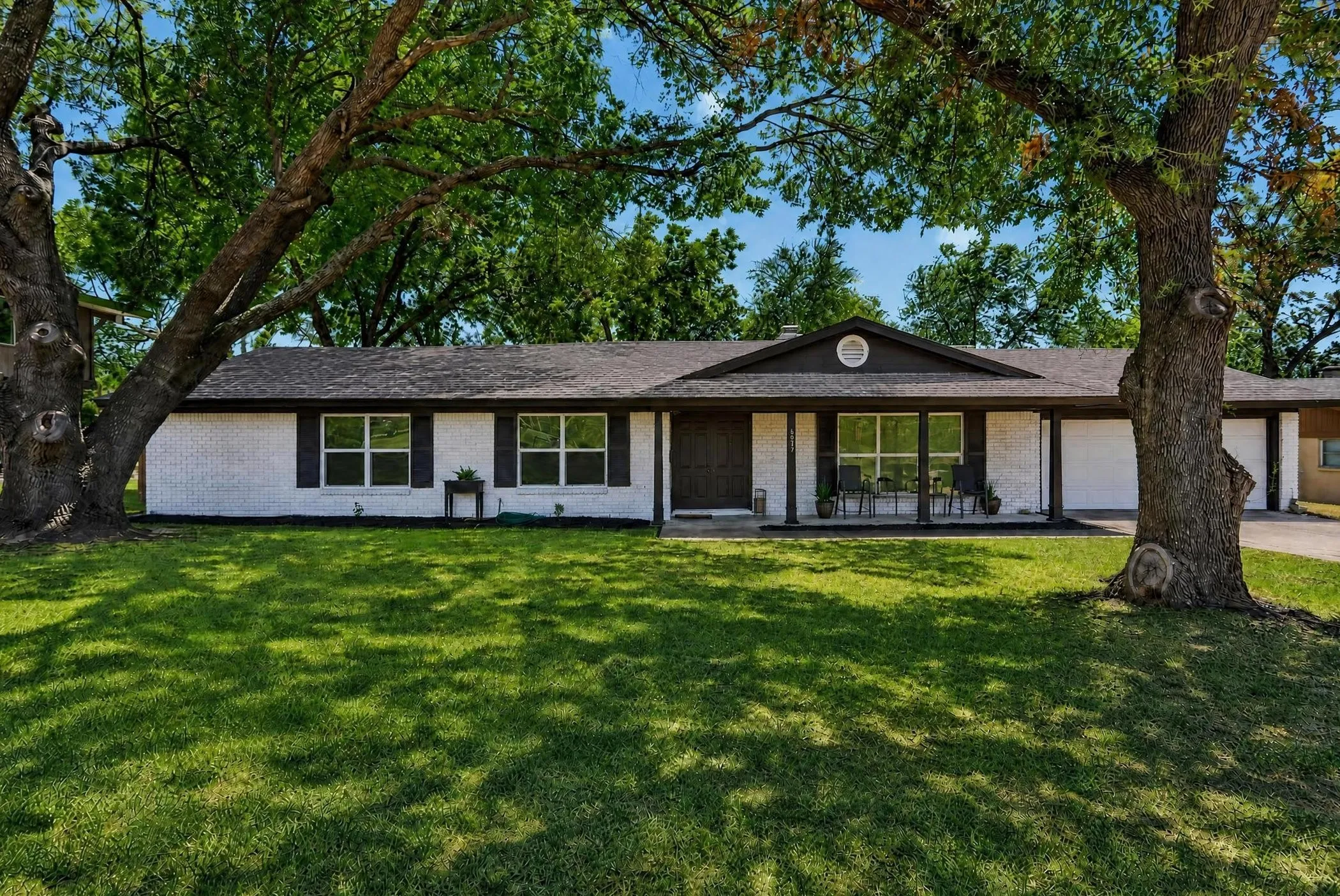 Contemporary single-story residence featuring a clean-lined exterior with white stucco and dark trim, large multi-pane windows, and a covered front porch