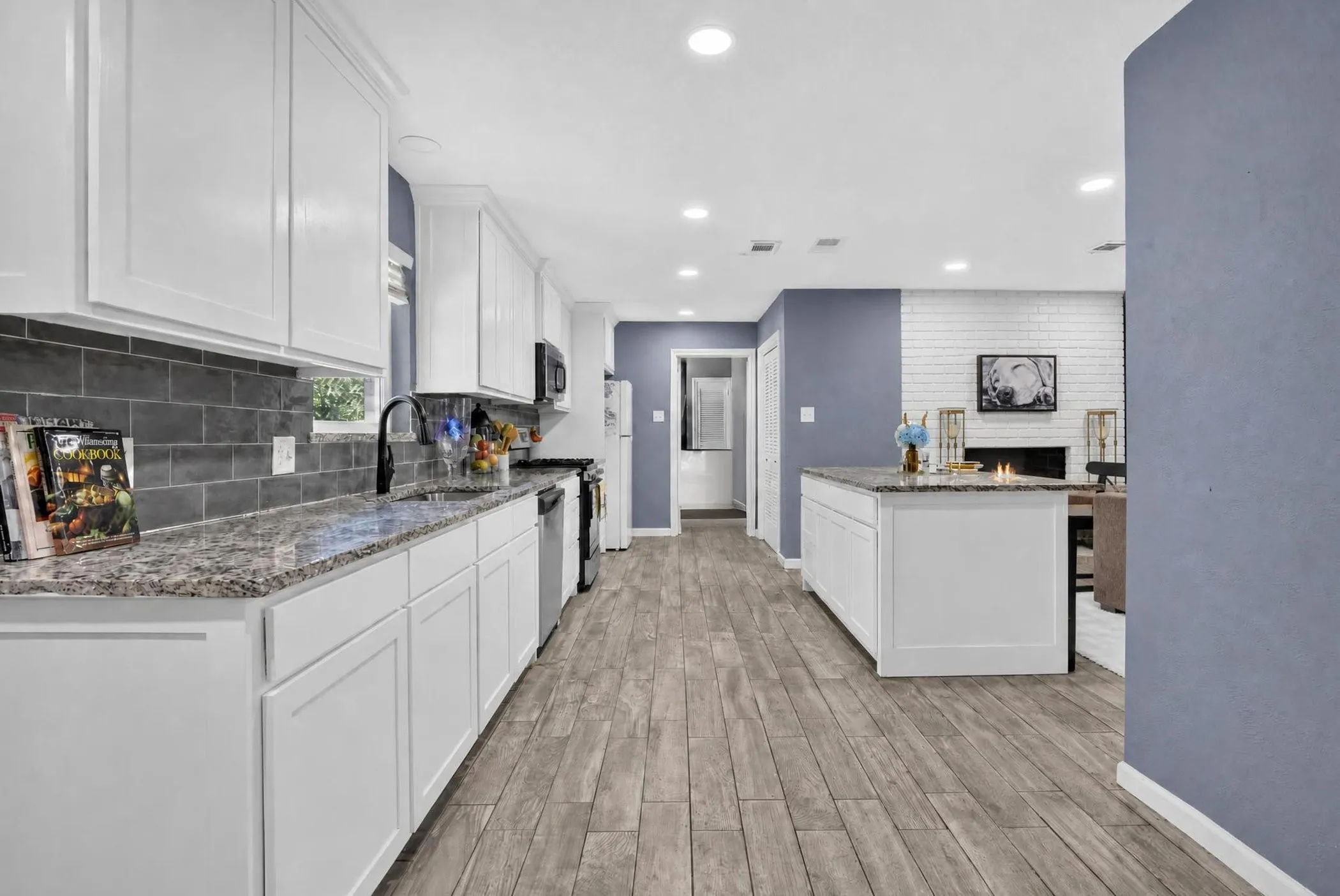 Modern kitchen featuring white shaker cabinetry, granite countertops, stainless steel appliances, and a gray subway tile backsplash
