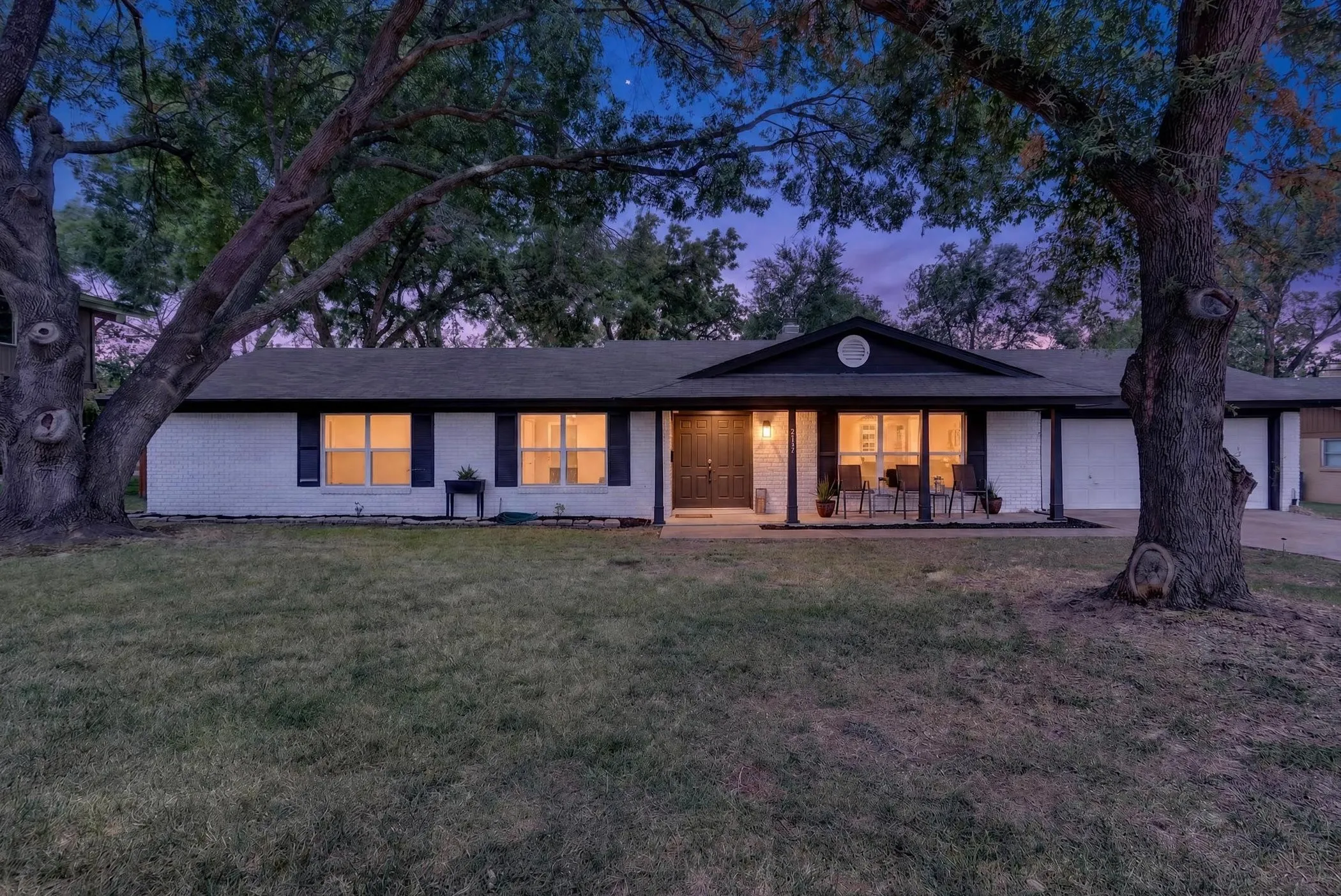 Modern single-story residence with clean-lined architecture, featuring a white exterior with black trim accents and multiple glass doors opening to the rear grounds