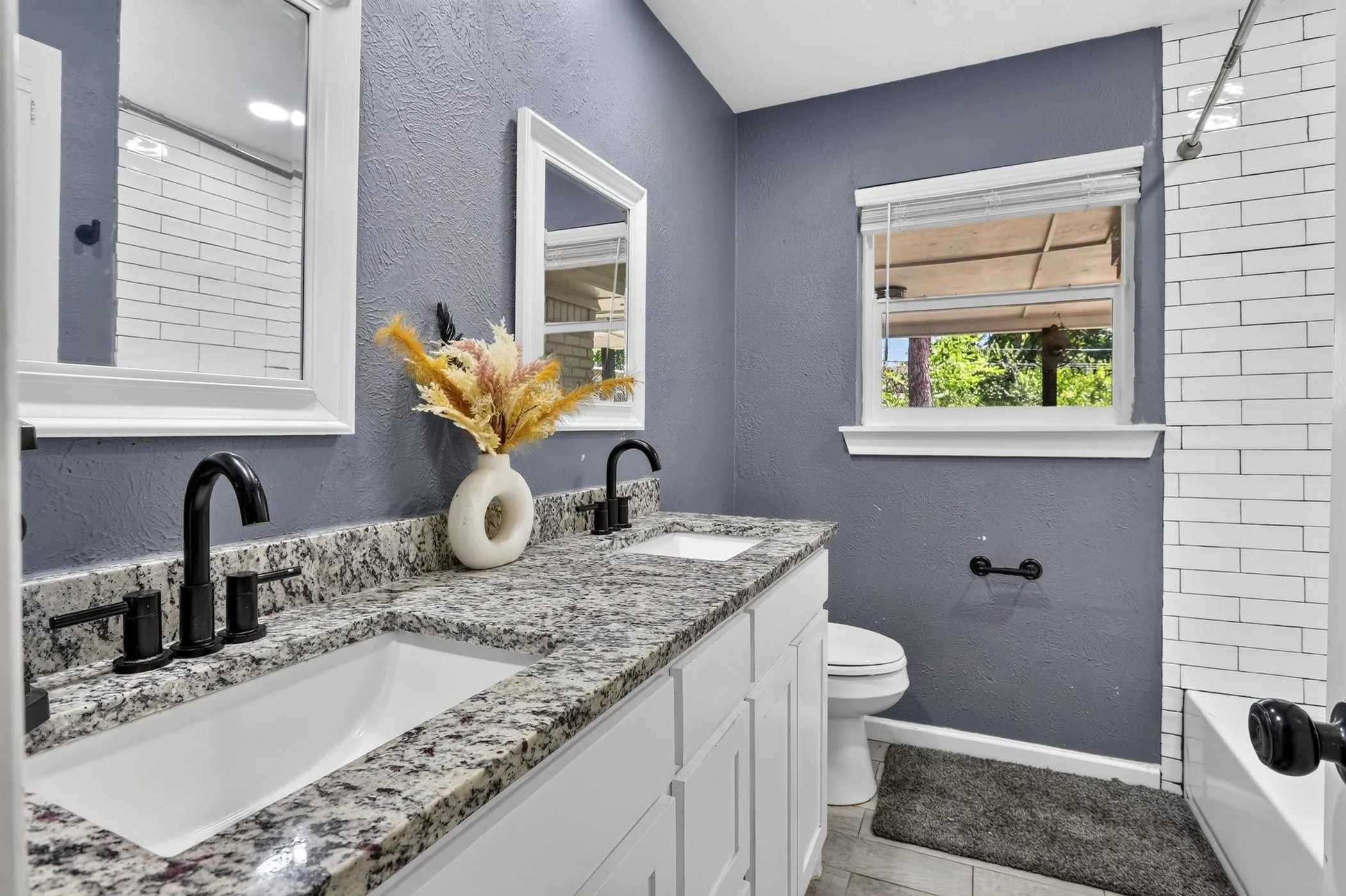 Double vanity with granite countertop, undermount sinks, and matte black fixtures