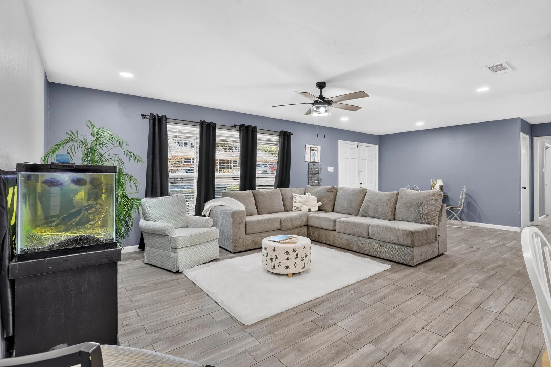 Spacious open-concept living area featuring a sectional configuration, plush seating arrangement, and neutral wood-finish flooring throughout