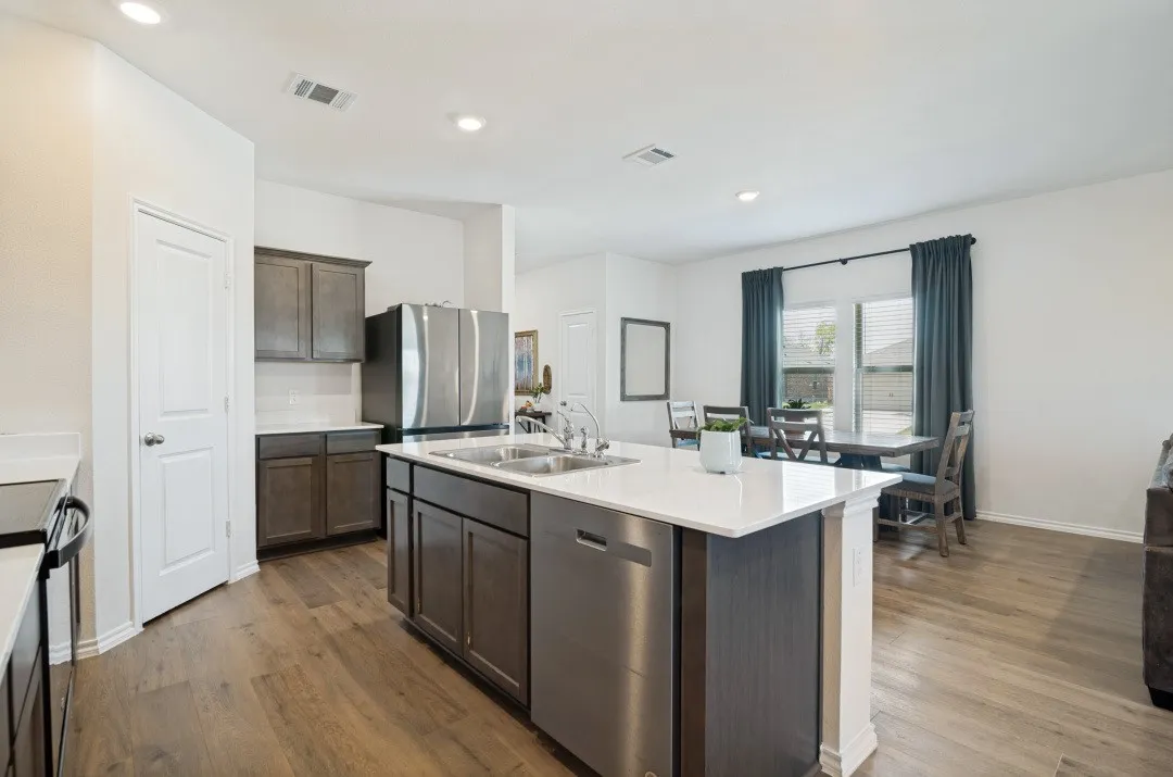 Kitchen featuring wood-finish flooring, recessed lighting, white quartz countertops, dark wood-finish cabinetry, and stainless steel appliances