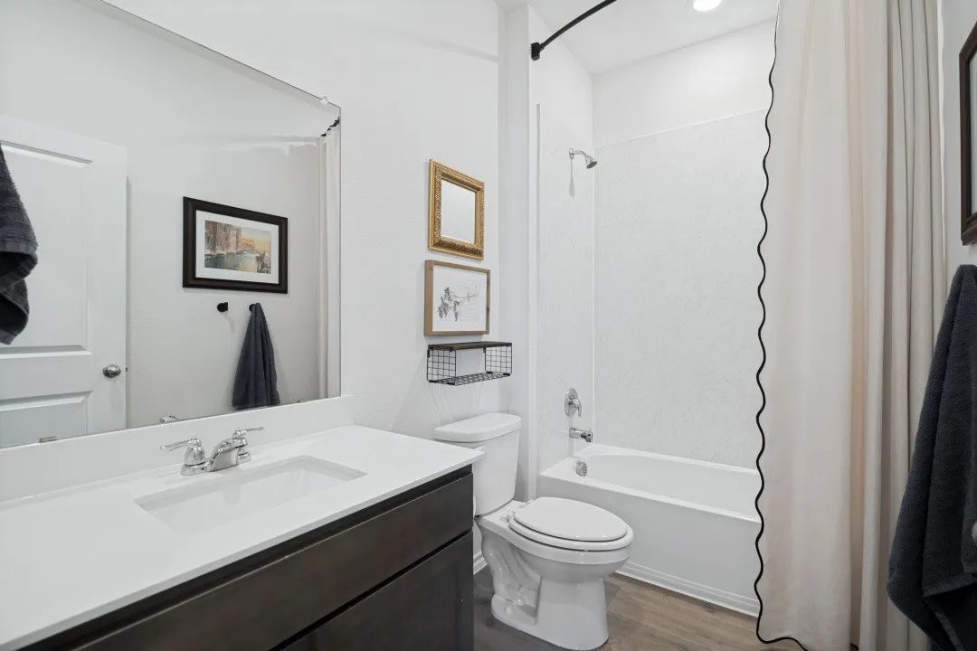 Single vanity with a white solid surface countertop and integrated sink, dark wood-finish cabinetry, and chrome fixtures