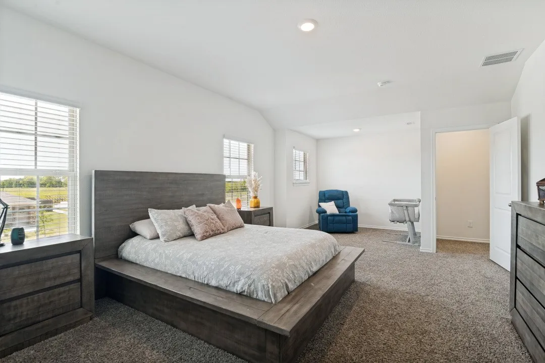 Spacious room with plush carpet flooring, recessed lighting, white walls, and multiple windows with blinds
