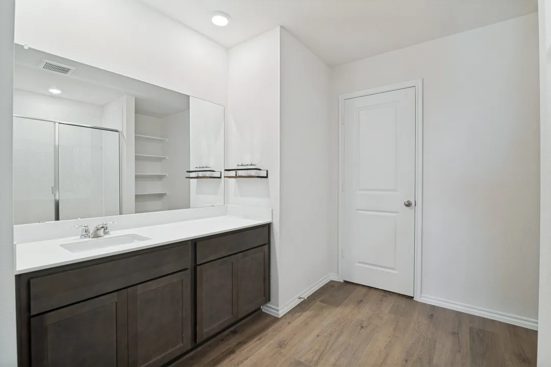 Vanity with an integrated sink, polished chrome faucet, and expansive wall-mounted mirror