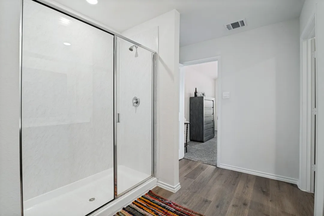 Walk-in shower with sliding glass door and chrome fixtures