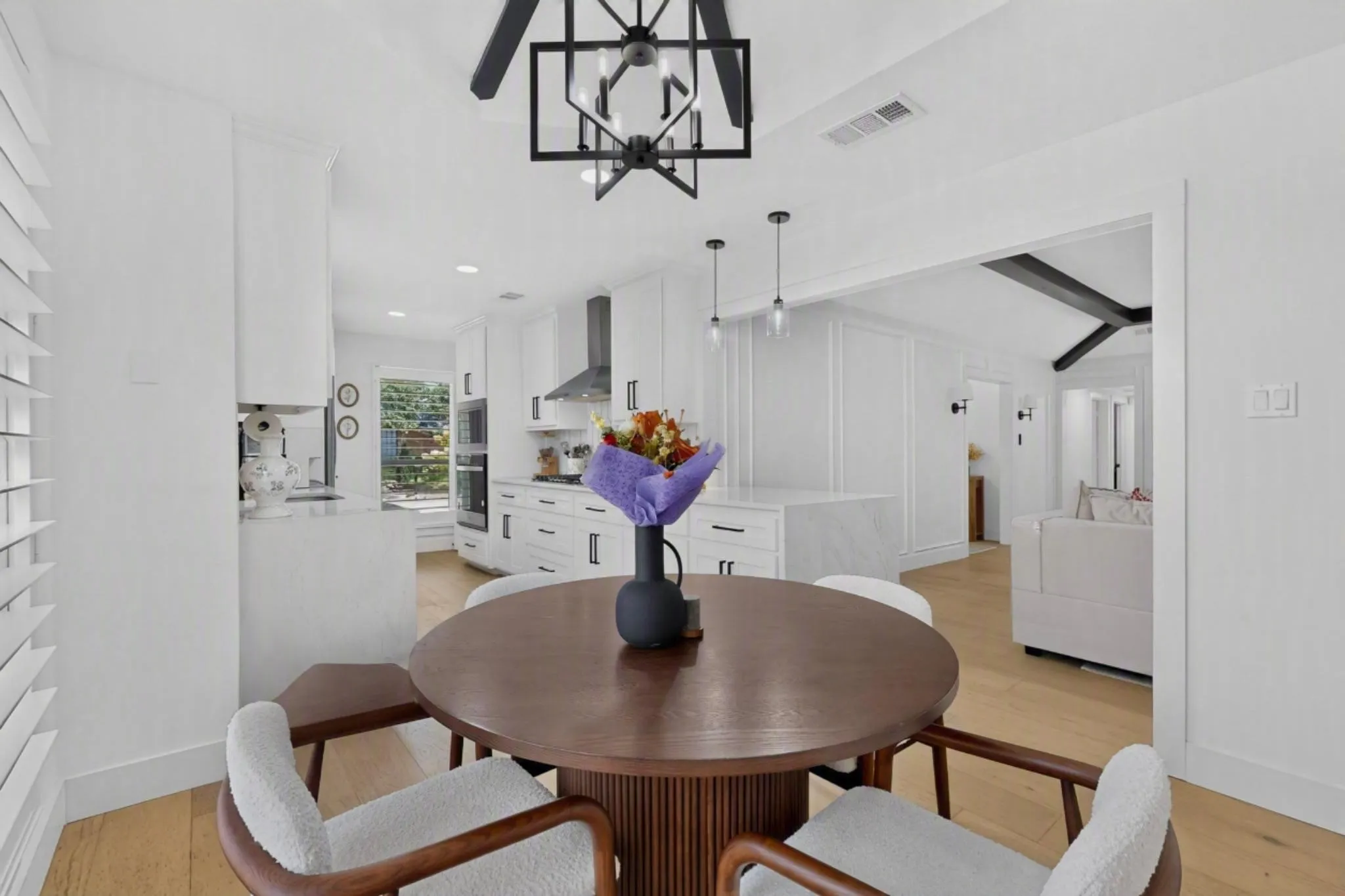 Bright kitchen featuring white cabinetry, integrated double ovens, and a contemporary range hood