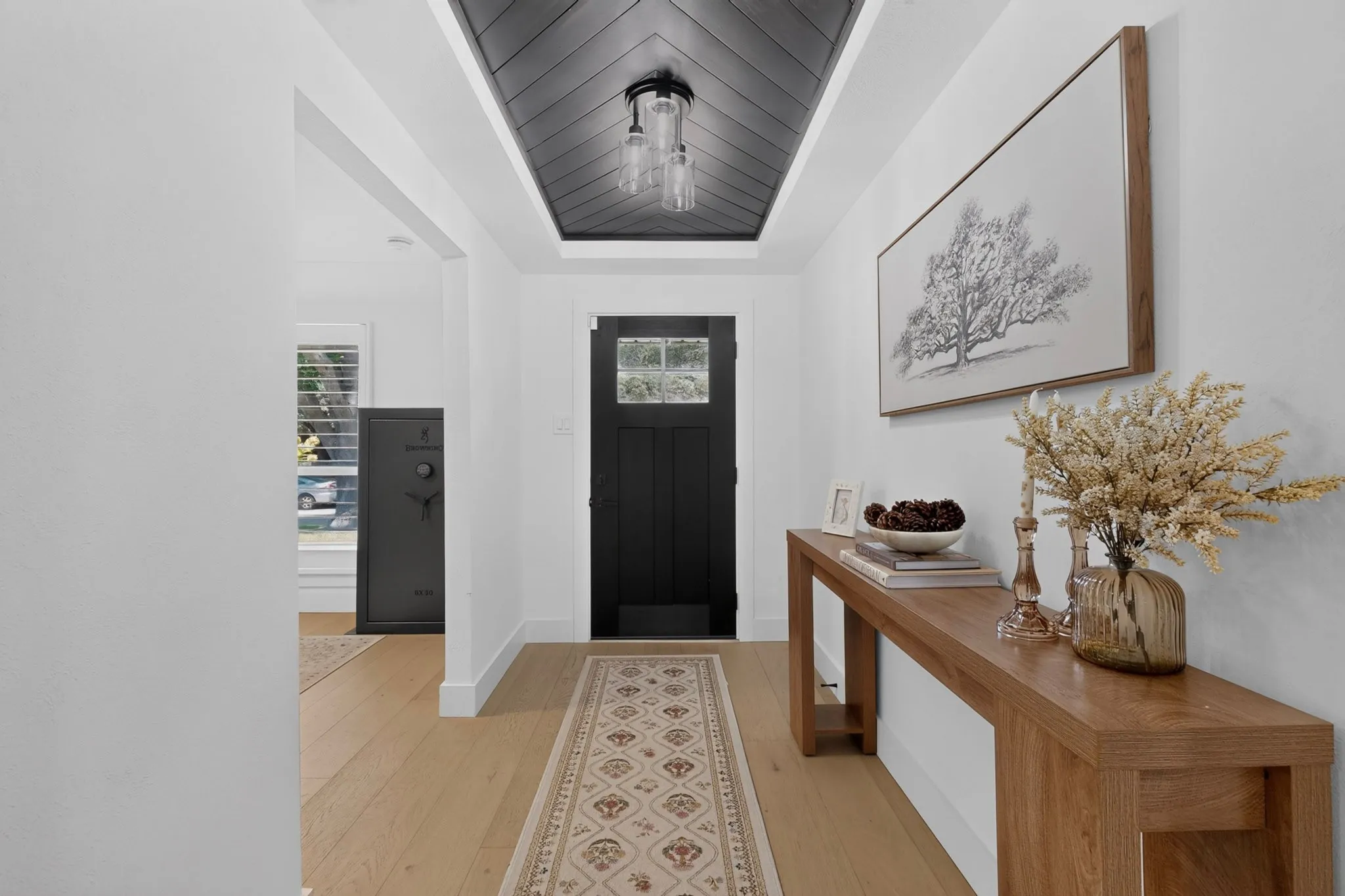 Entryway with wood-finish flooring, a black front door with glass inserts, and a decorative ceiling fixture