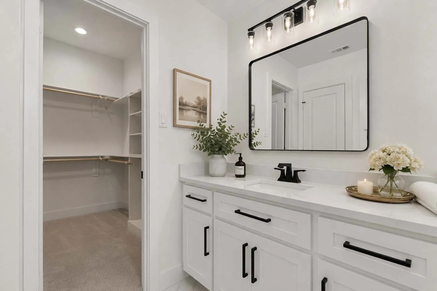 White vanity with shaker-style cabinetry, black hardware, and a single-basin sink