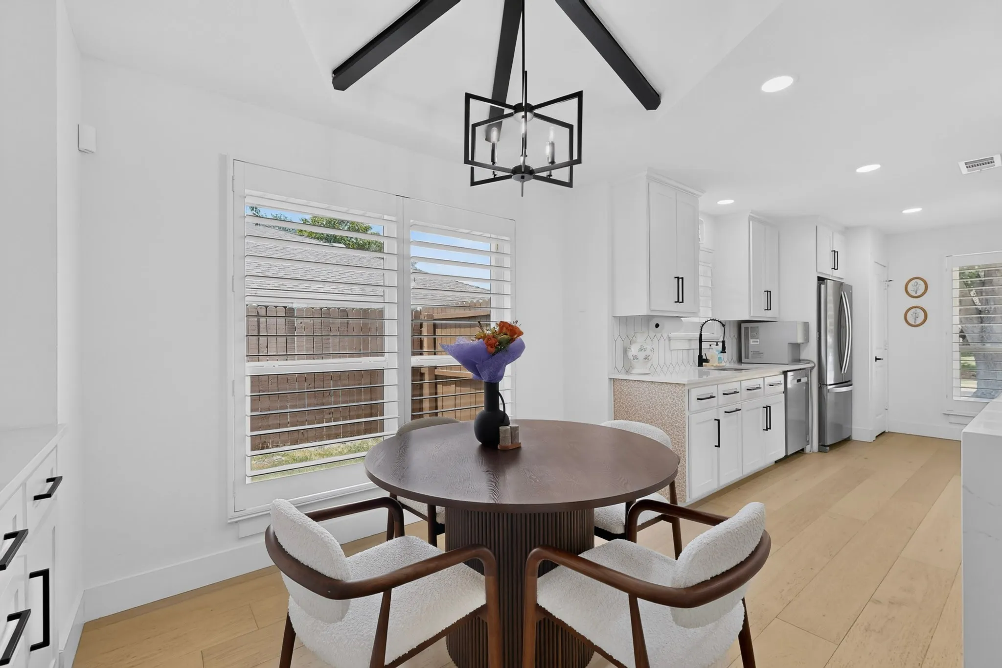 Contemporary kitchen with white cabinetry, black hardware, stainless steel appliances, and wood-finish flooring