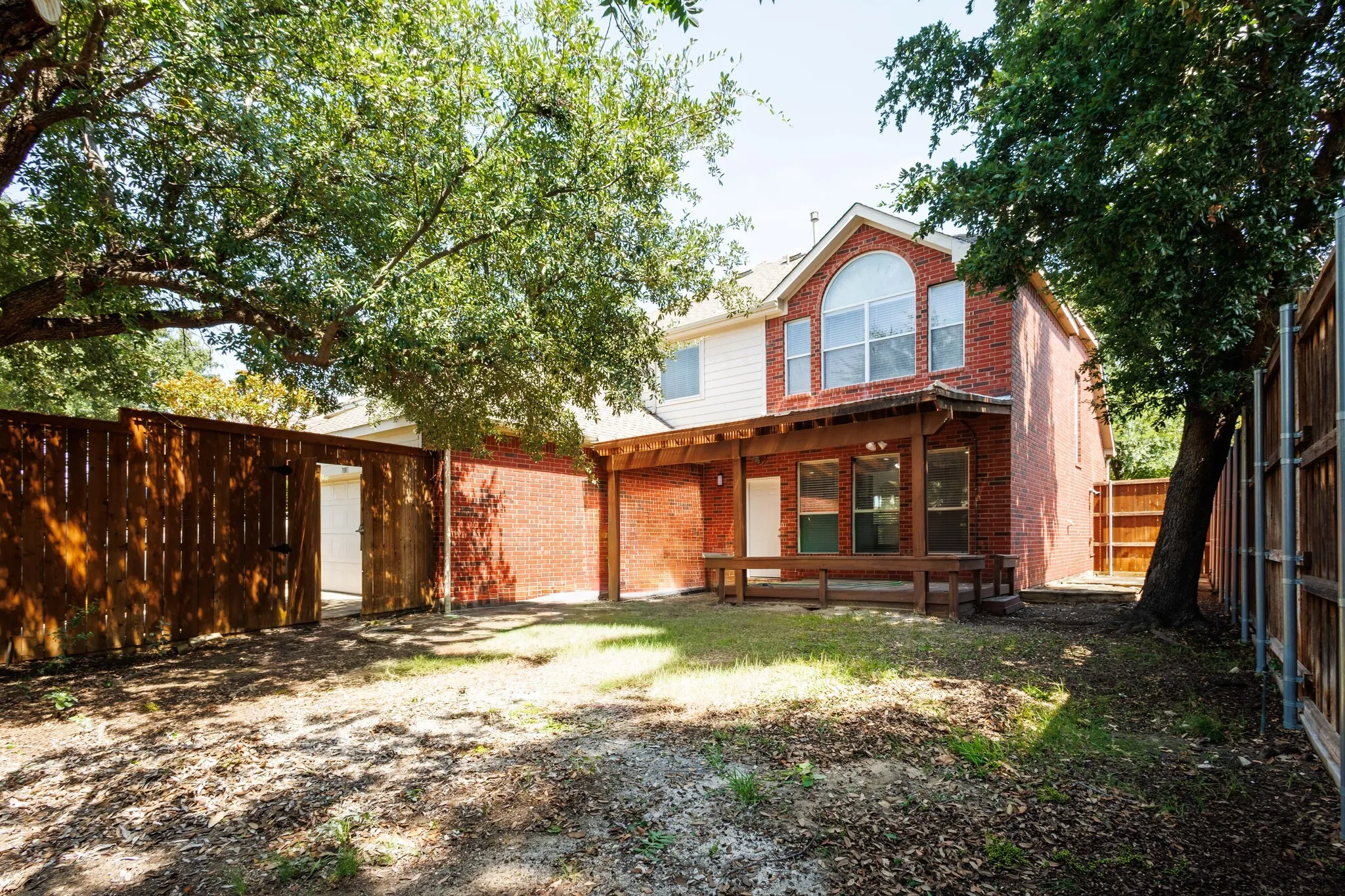 Expansive backyard featuring a brick exterior and a covered patio with integrated seating