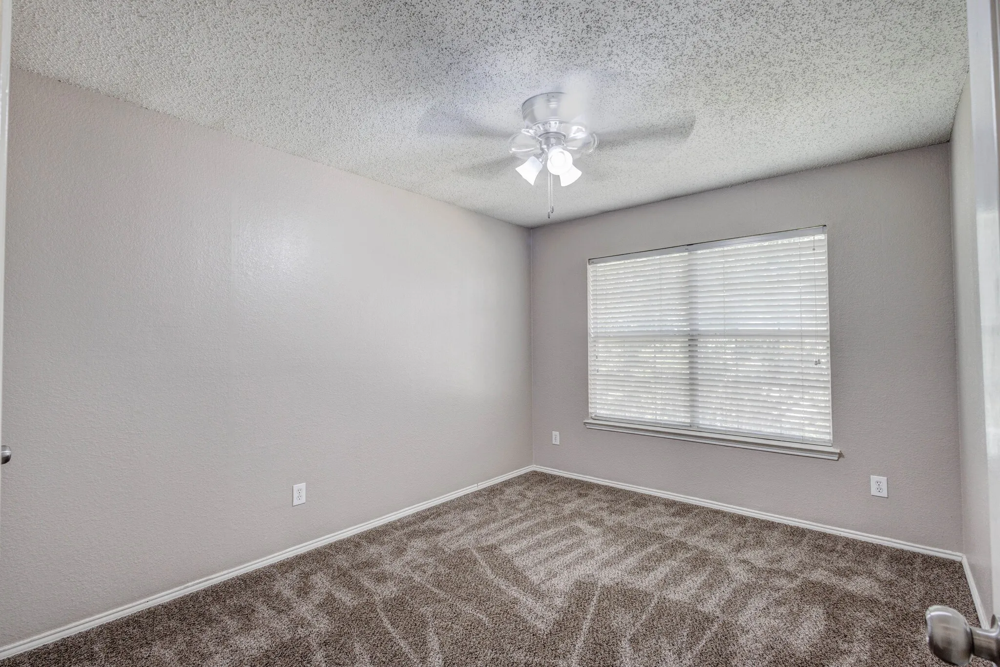 Bedroom featuring neutral wall tones, patterned carpet flooring, a window with blinds, a ceiling fan with light fixture, and white trim