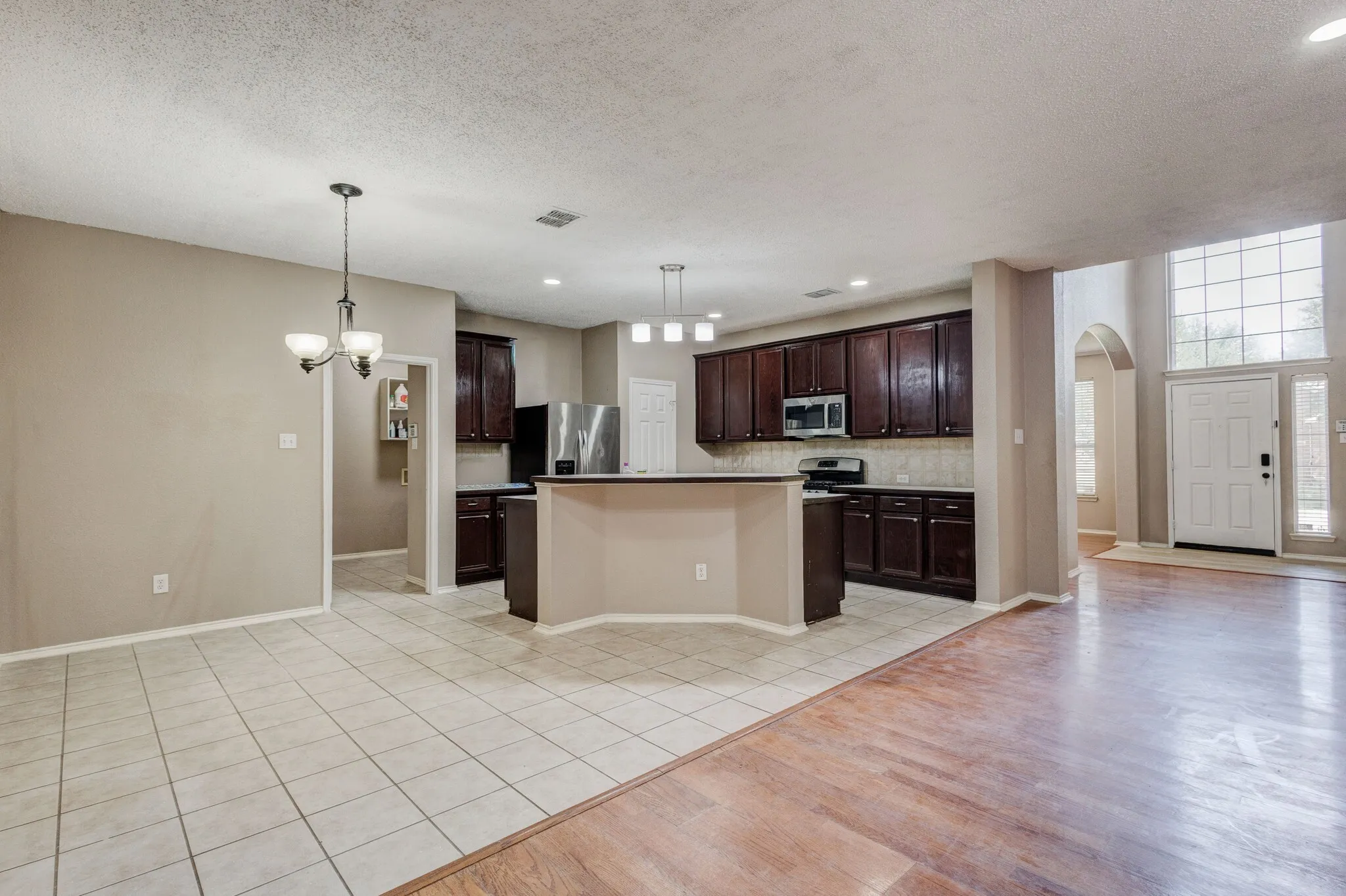 Open-concept living space featuring a kitchen with dark wood-finish cabinetry, a central island, and stainless steel appliances