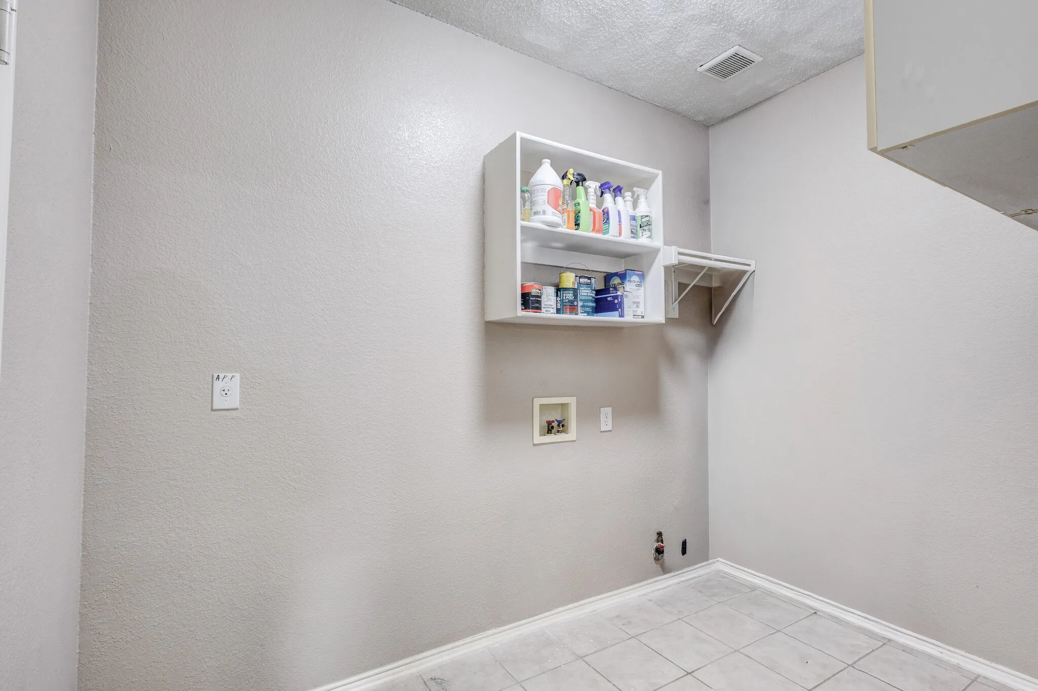 Utility area featuring tile flooring, neutral wall tones, and built-in wall shelving