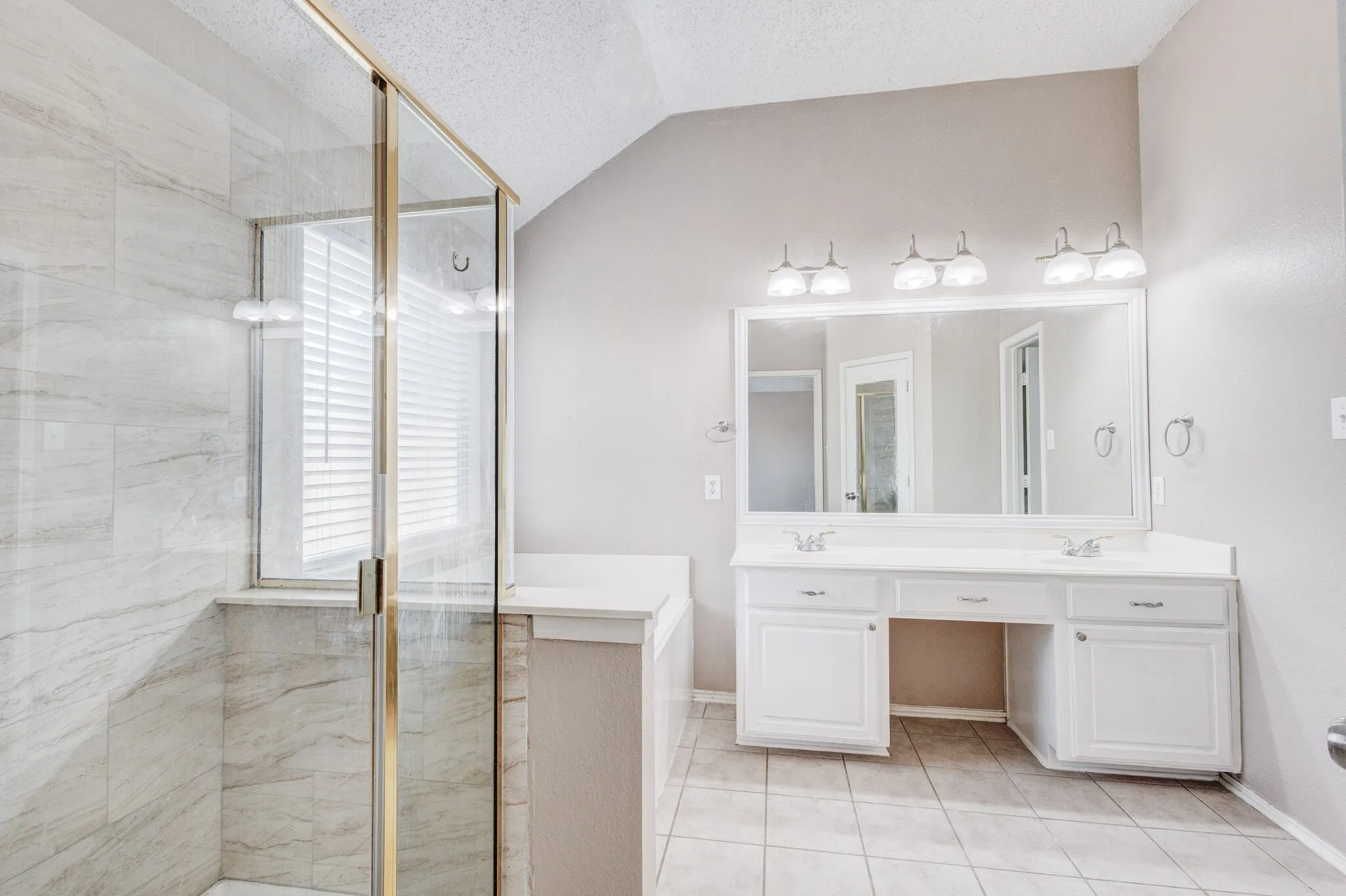 Spacious bathroom featuring a dual vanity with white cabinetry and an expansive mirror
