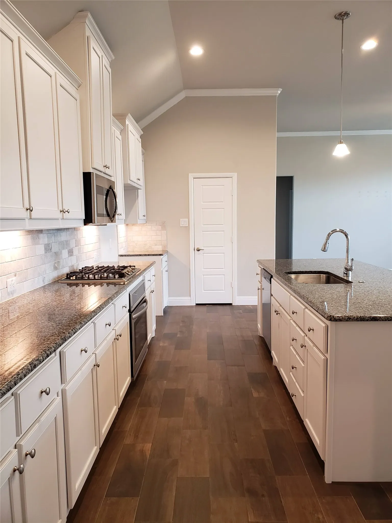Kitchen with white cabinetry, dark granite countertops, tile backsplash, and wood-finish flooring