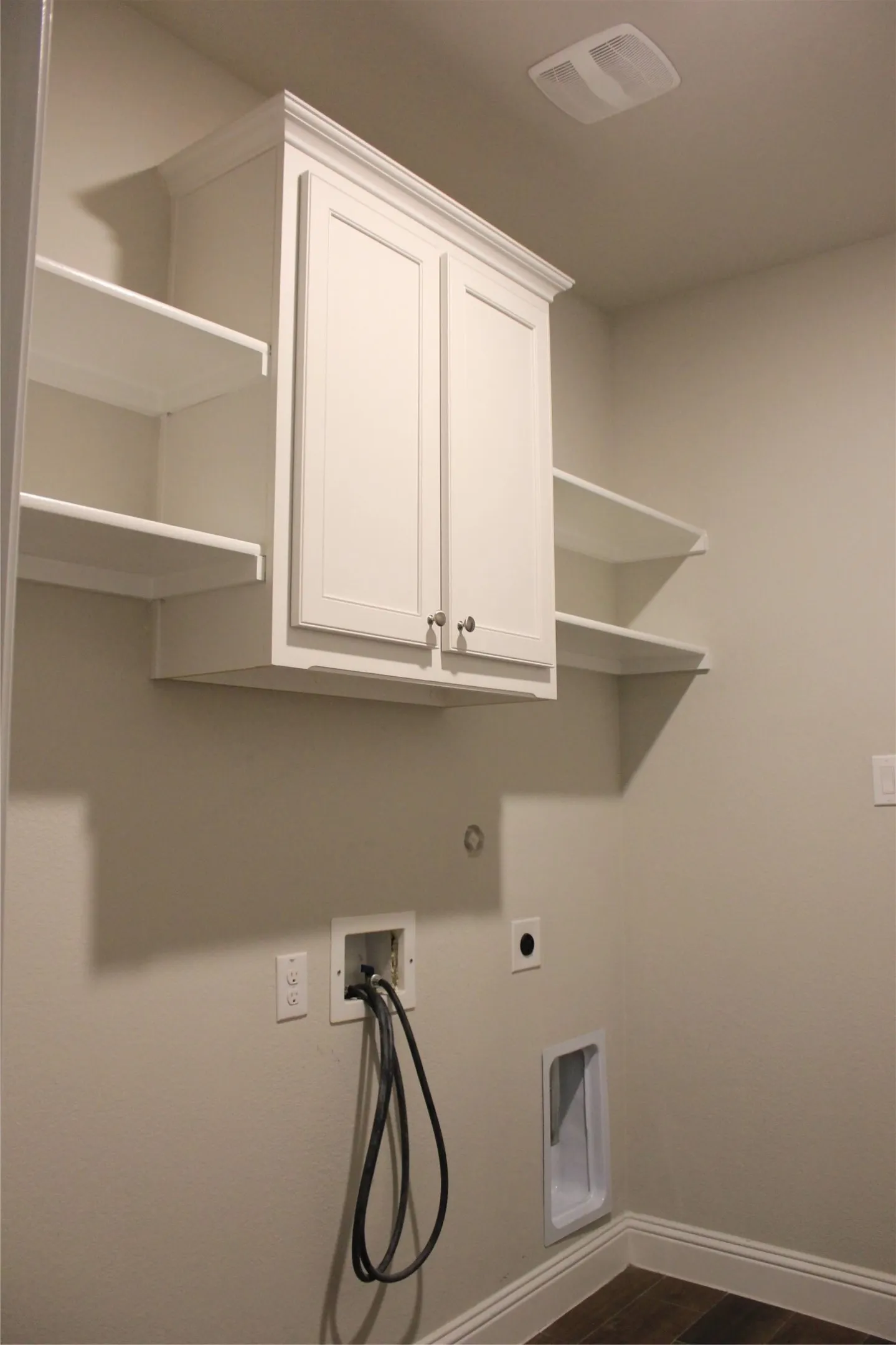 Utility room with Built-in white cabinetry with crown molding, open shelving, and wood-finish flooring