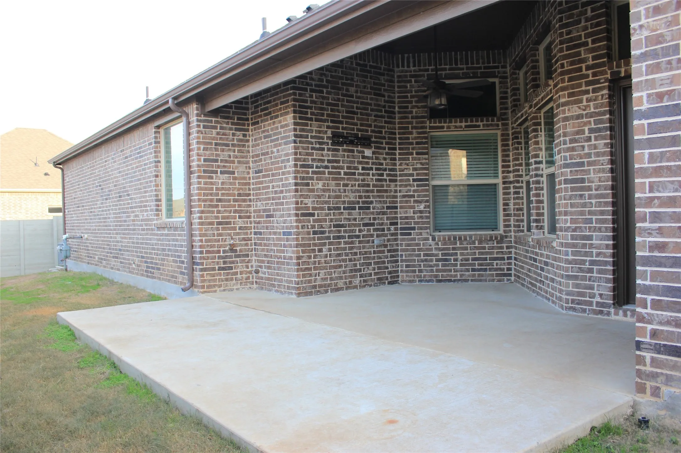 Covered concrete patio with brick exterior and recessed lighting