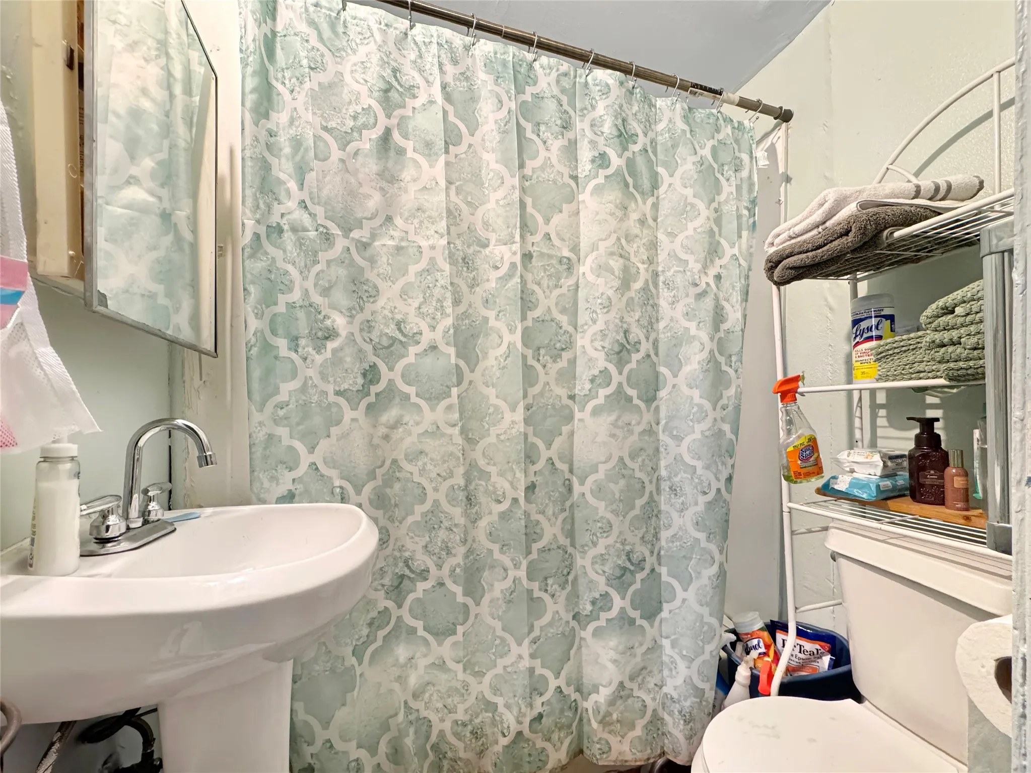 Pedestal sink with chrome faucet, wall-mounted mirrored medicine cabinet, and toilet