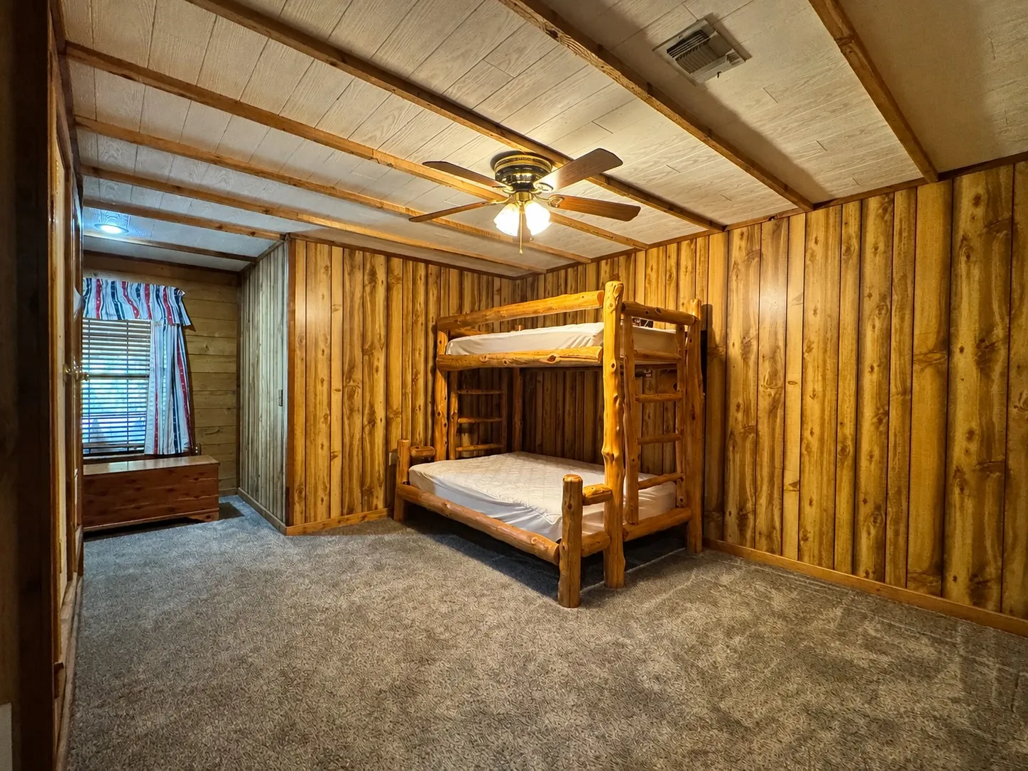 Interior room featuring wood-paneled walls and a matching wood-paneled ceiling with exposed beams