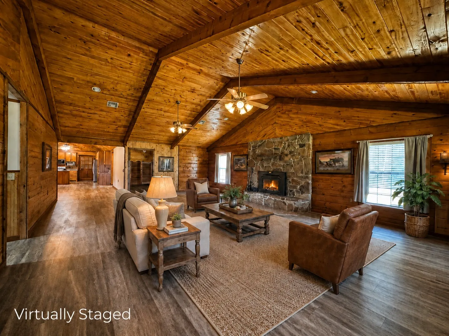 Spacious living area featuring a stone fireplace, wood-finish flooring, and vaulted wood-paneled ceilings with exposed beams