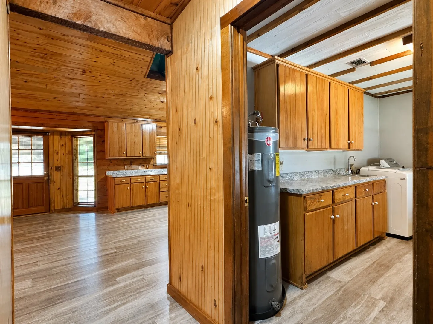 Utility room featuring a built-in sink, wood-finish cabinetry, and a countertop with a stone-look finish