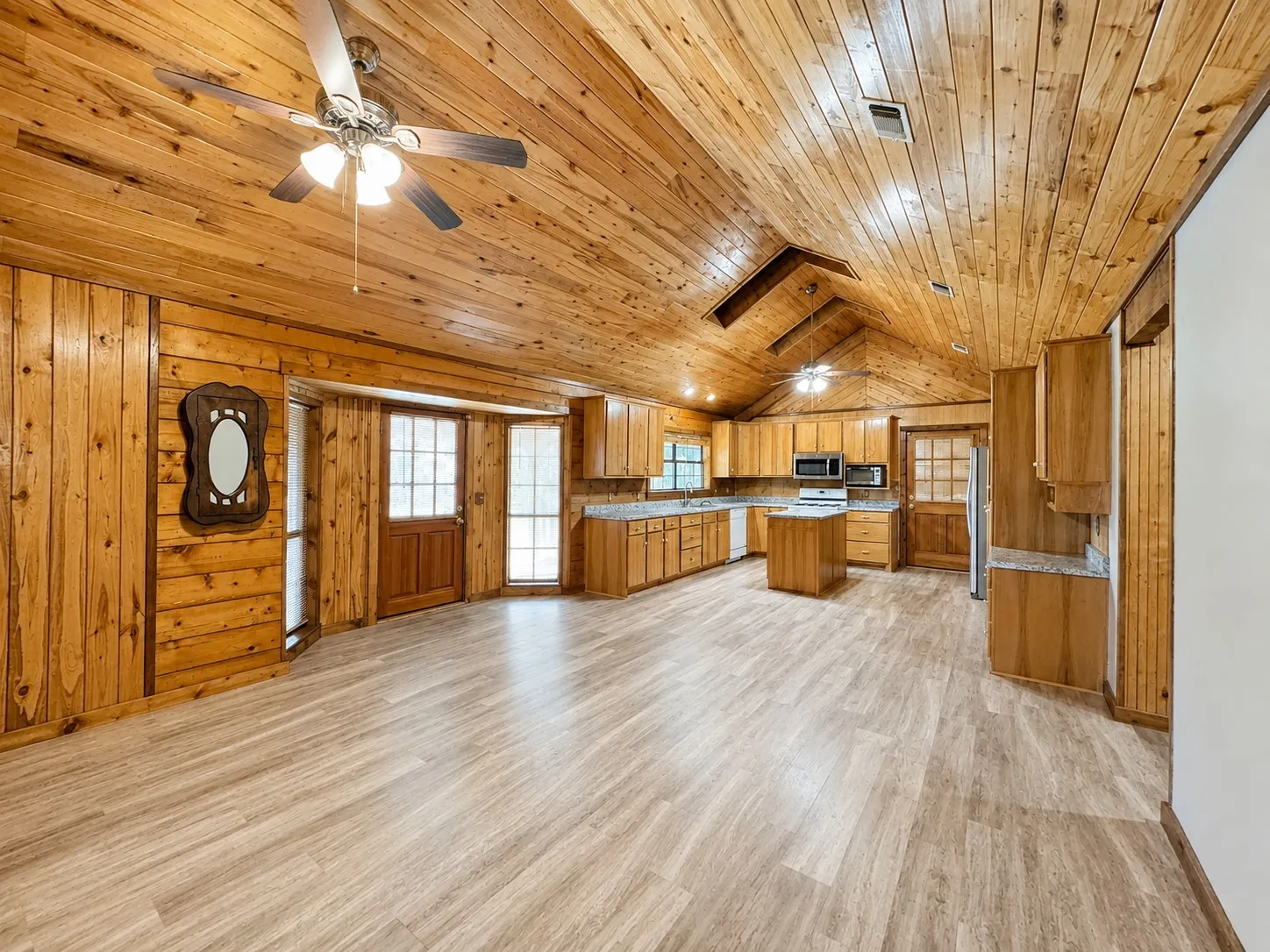 Vaulted wood-paneled ceilings with exposed beams, wood-finish flooring, and a kitchen island with storage