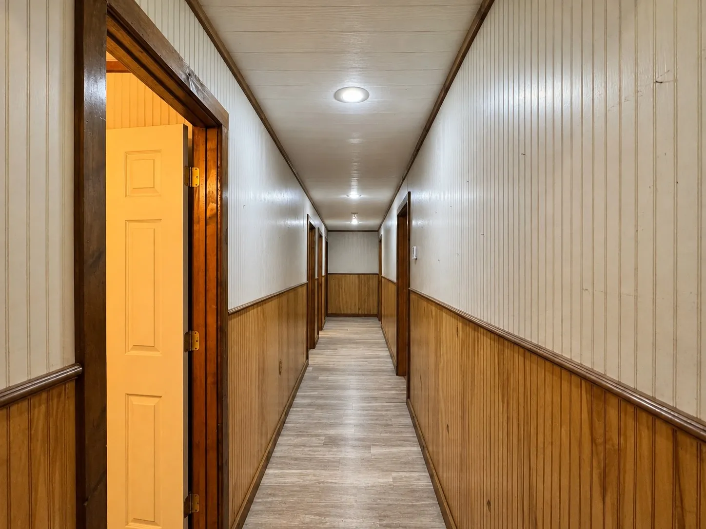 Hallway featuring beadboard paneling, wood-finish flooring, recessed lighting, and multiple paneled doors with wood trim
