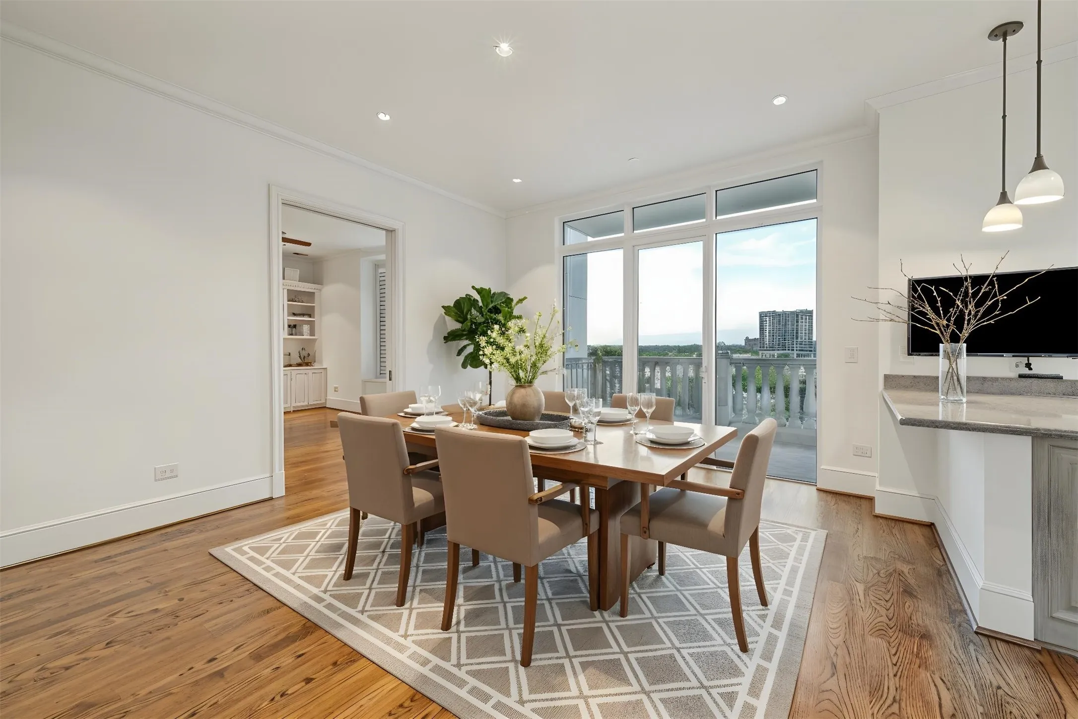 View of dining area from wide interior hallway to west-facing balcony (virtually staged)