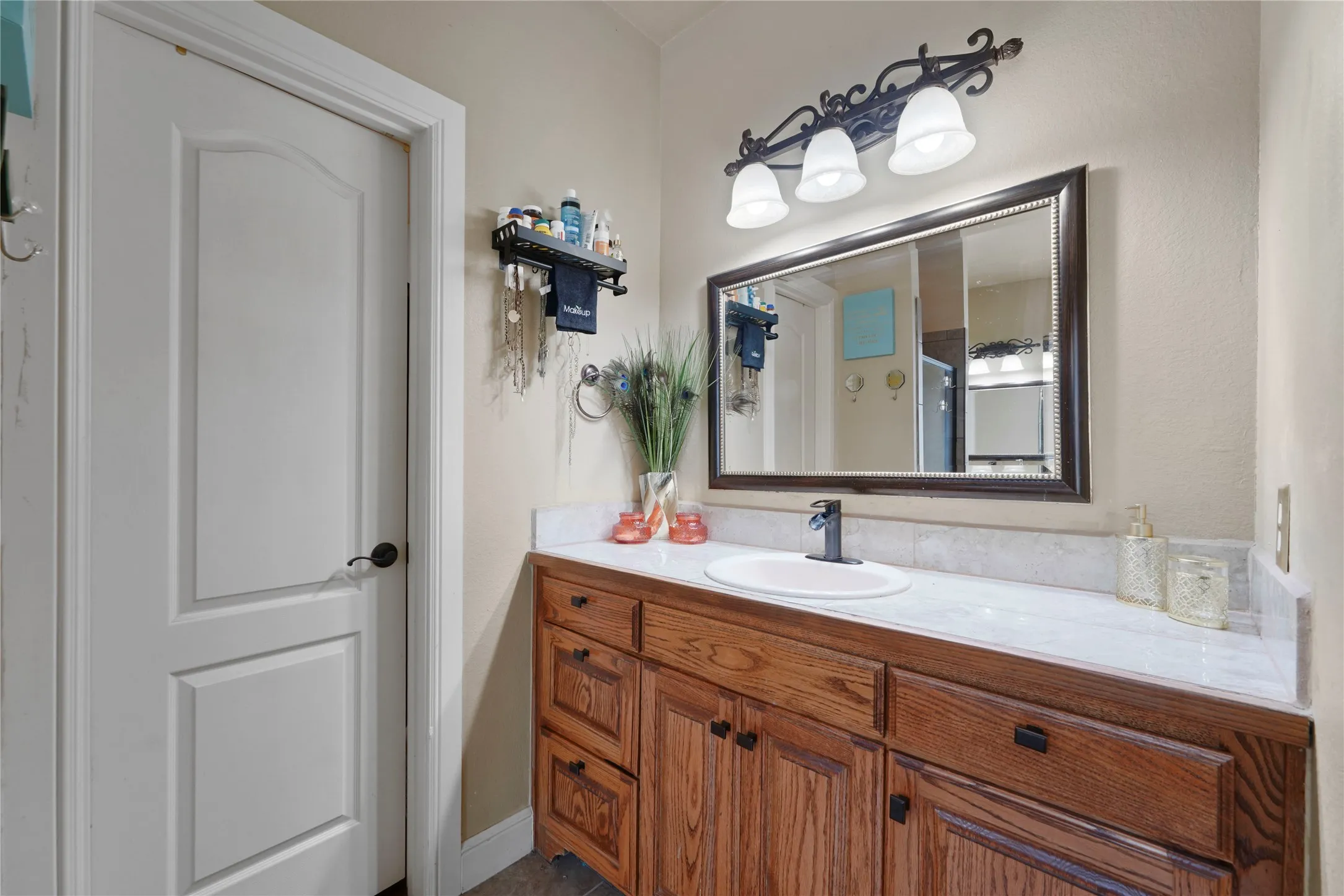 Vanity with wood-finish cabinetry, integrated sink, and dark-toned faucet